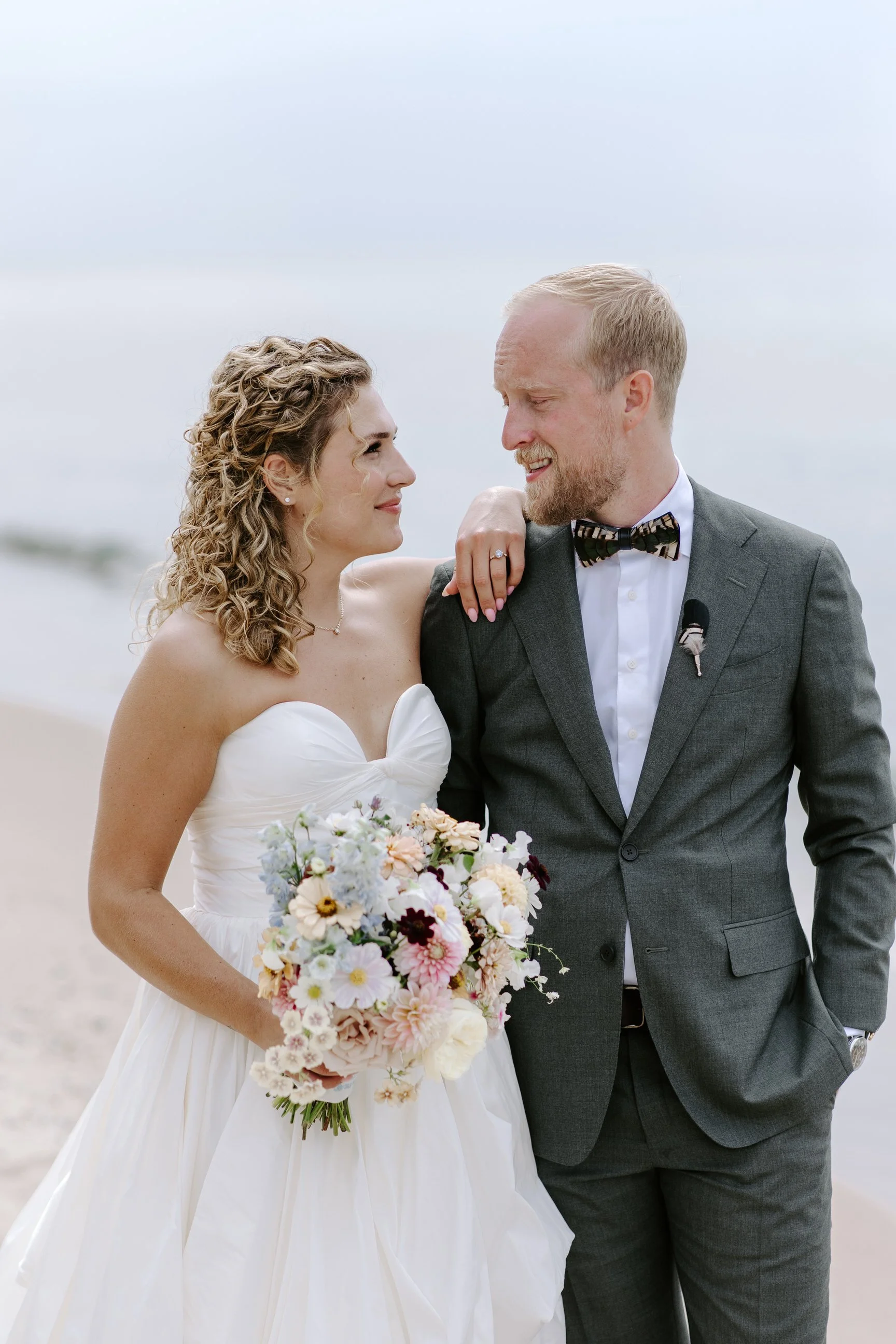 Bride and groom on the lake shores enjoying their portrait session at their high end wedding