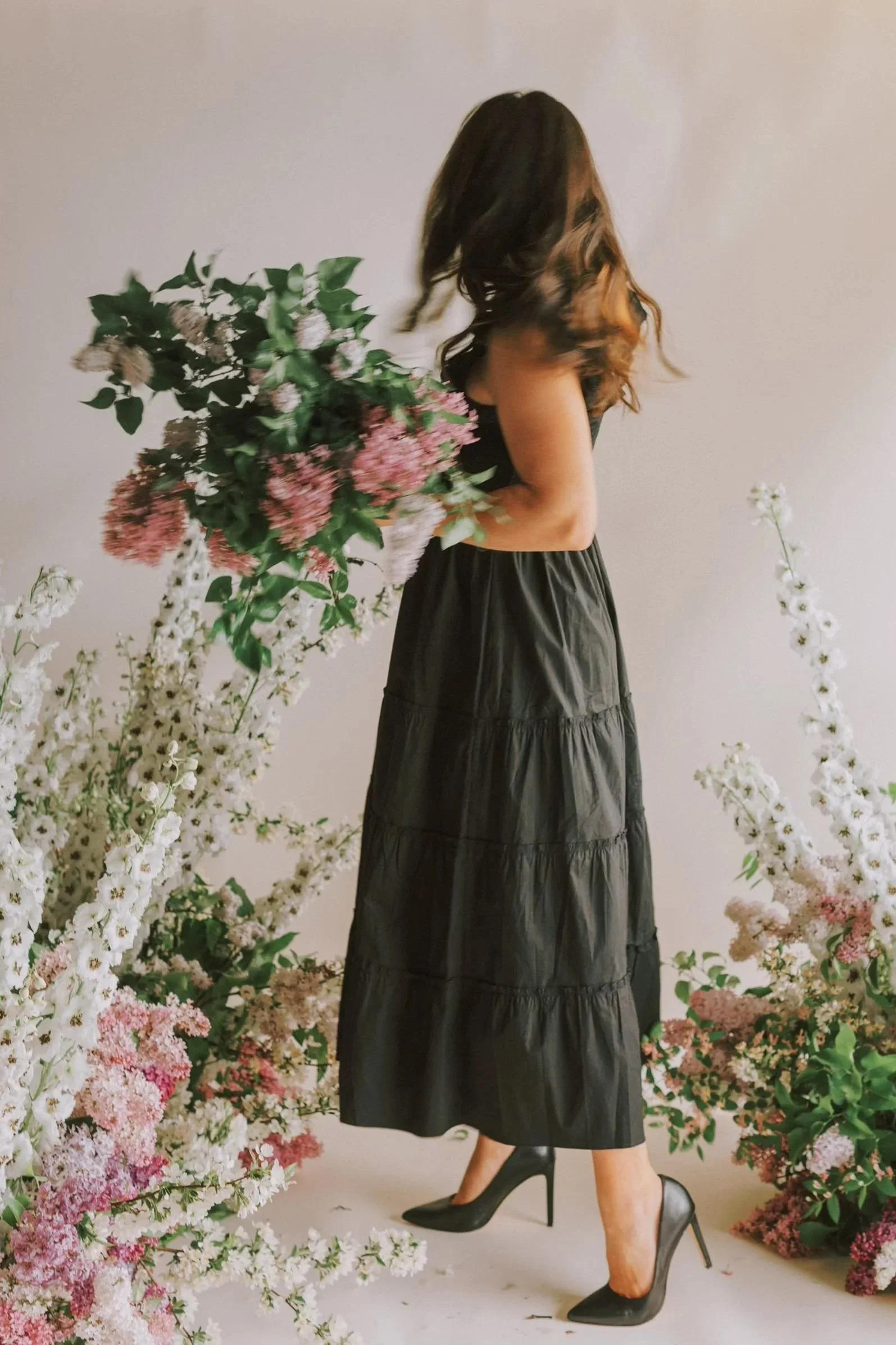 Rhiannon Bosse standing among pink and white flowers against a plain beige background.