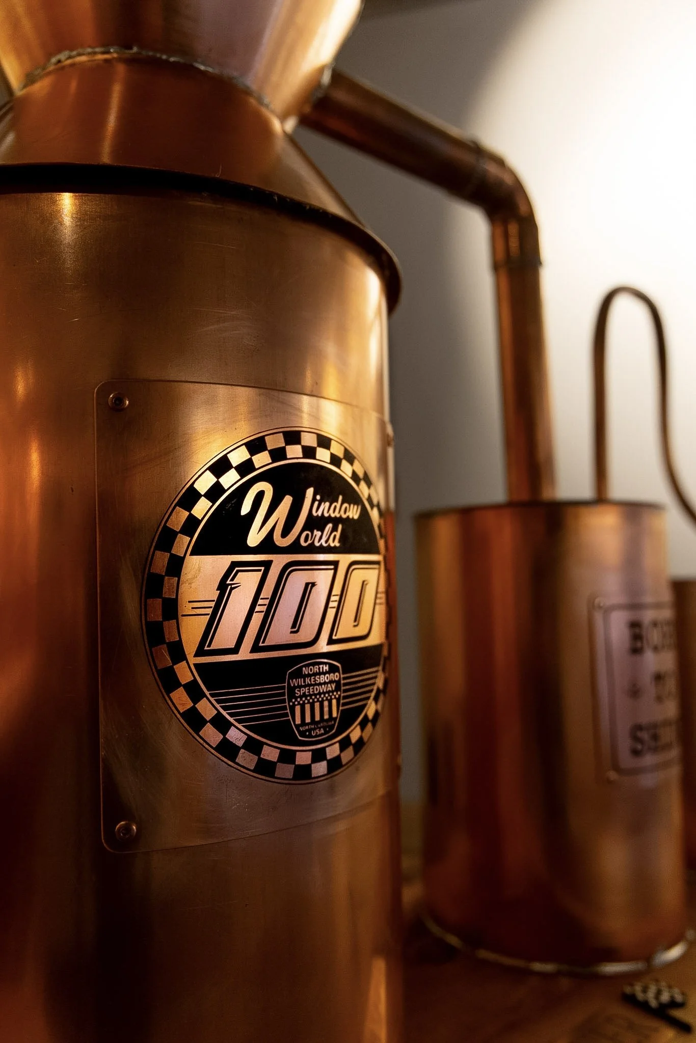 Close-up of a metallic item with a racing checkered flag logo, text reading "Window World 1000" and additional logo text "North Wilkesboro Speedway".