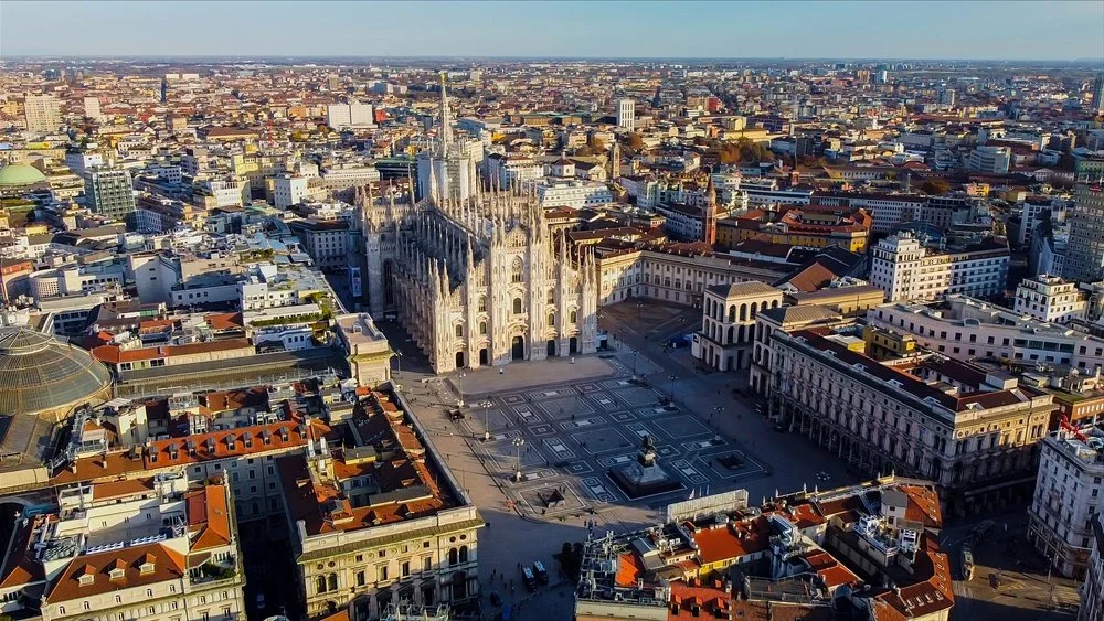 Veduta aerea del Duomo di Milano con piazza, edifici storici e moderni, e la città circostante