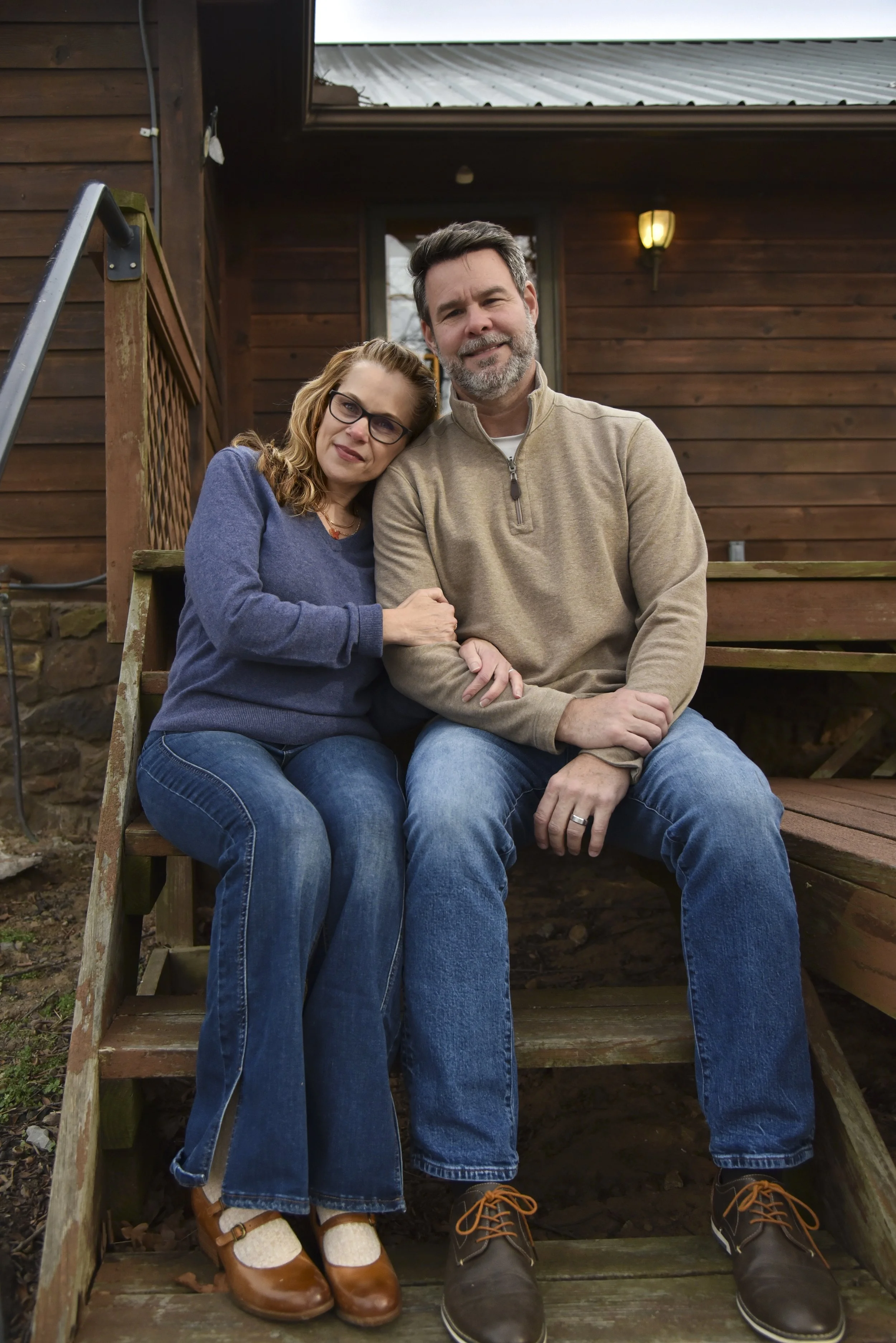 couple sitting on stairs in front of log cabin