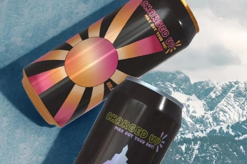 Two energy drink cans with black, pink, and orange designs, placed on a blue surface with a mountain landscape background.