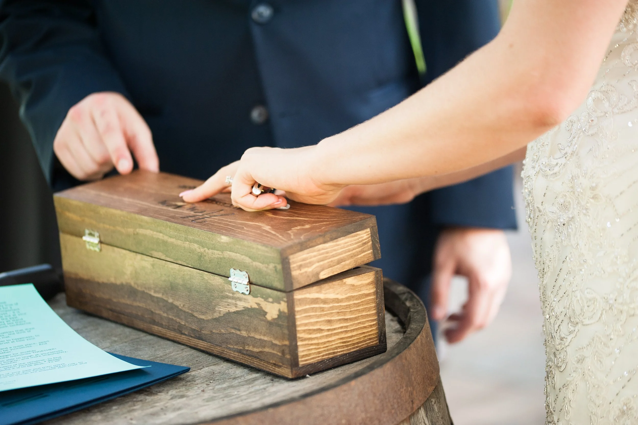 A couple sealing a handcrafted wooden memory box during their Humanist wedding ceremony, planned by All Things Joyful.