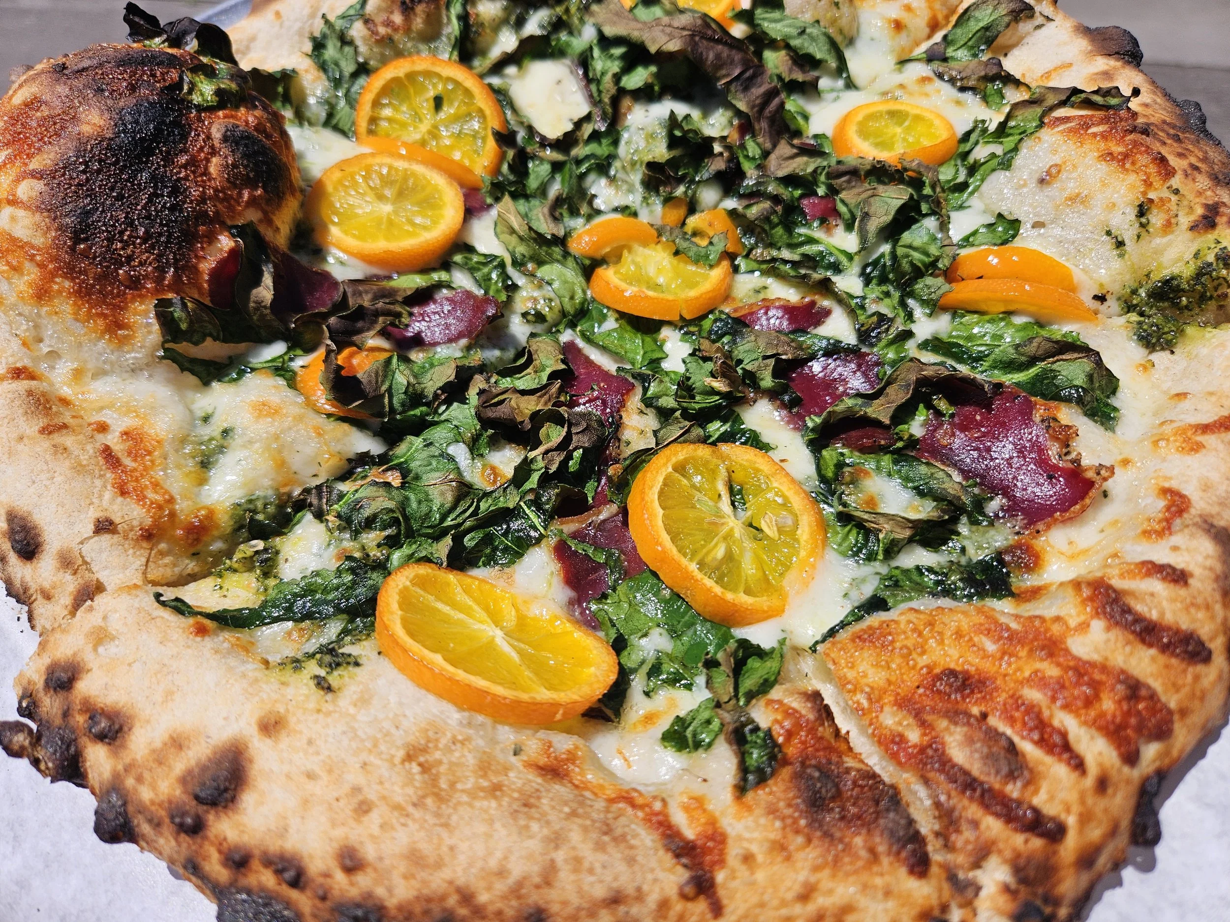 Wood fired pizza with duck prosciutto, kumquats, and arugula
