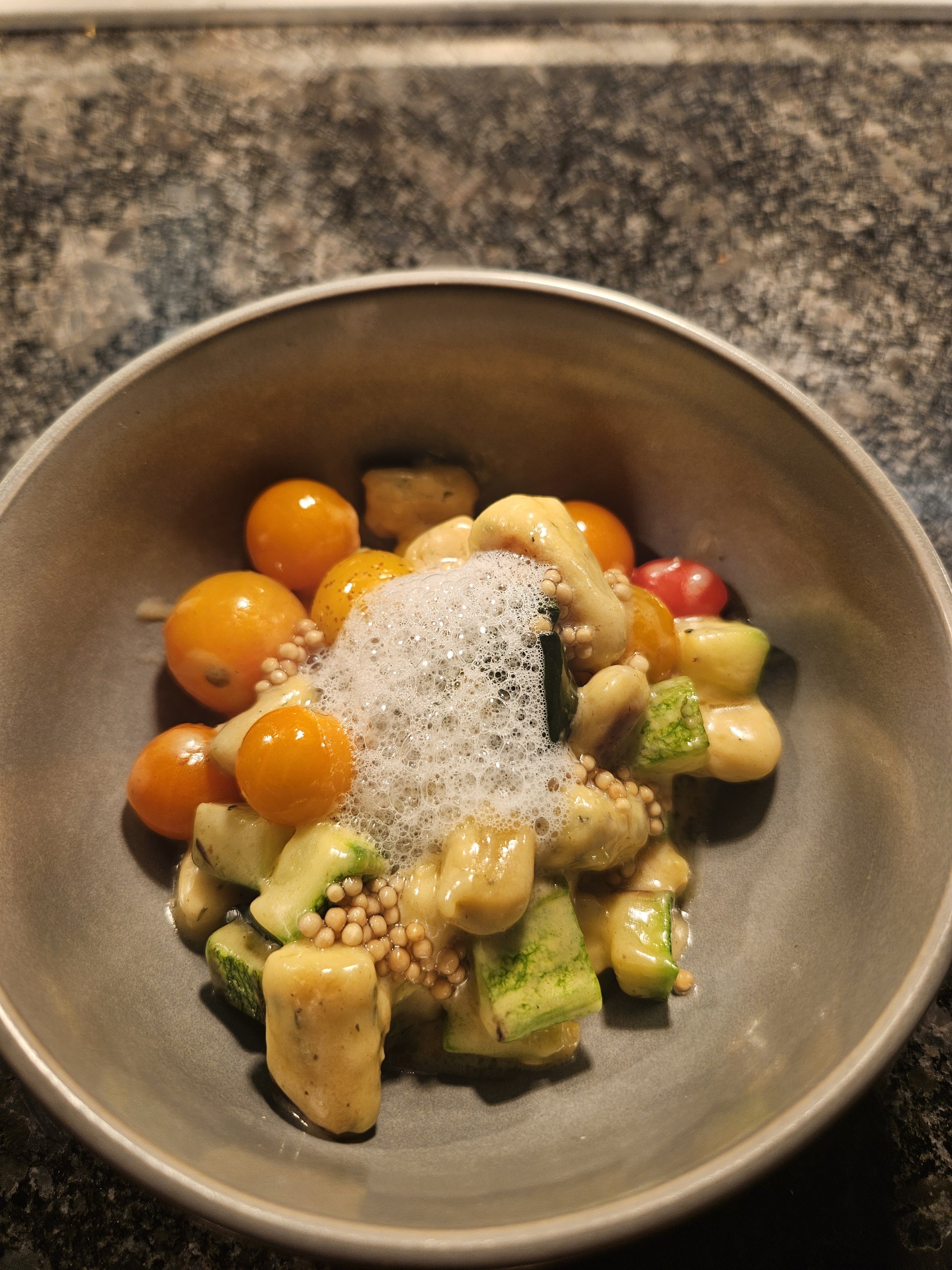 Gnudi with cherry tomatoes, zucchini, and garlic milk foam