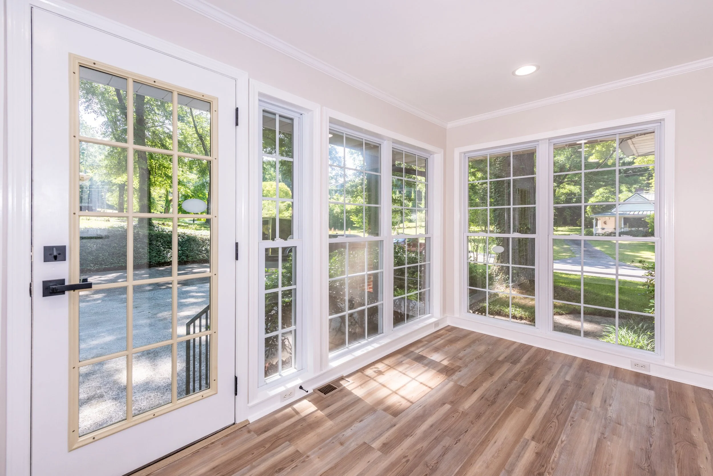 The spacious sunroom welcomes you from the driveway and is filled with natural morning light through its floor-to-ceiling windows. Updated flooring, fresh paint, and modern lighting create a bright and inviting introduction to the home.