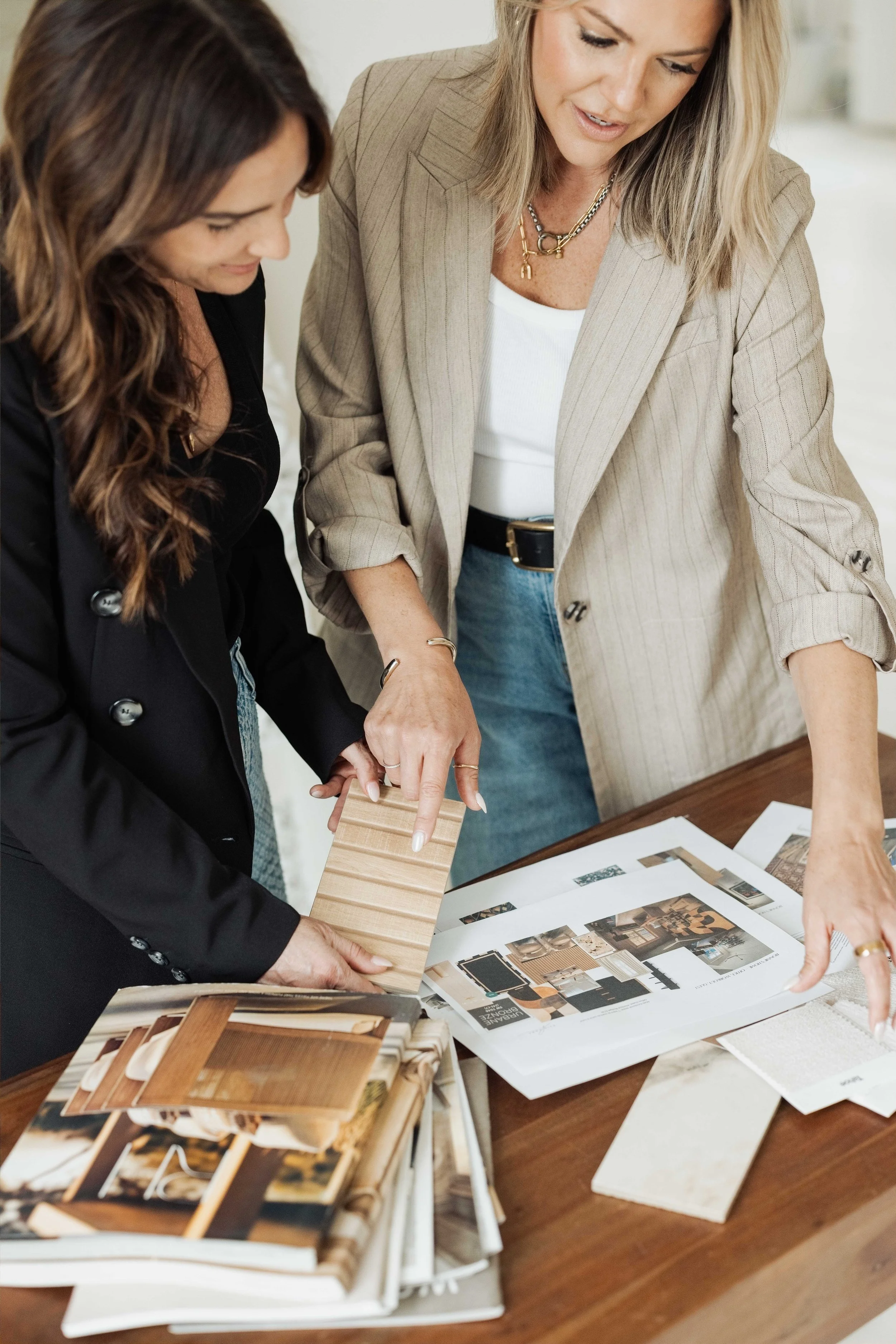 Ashley Walkley looking at interior design or home renovation magazines and material samples on a table.