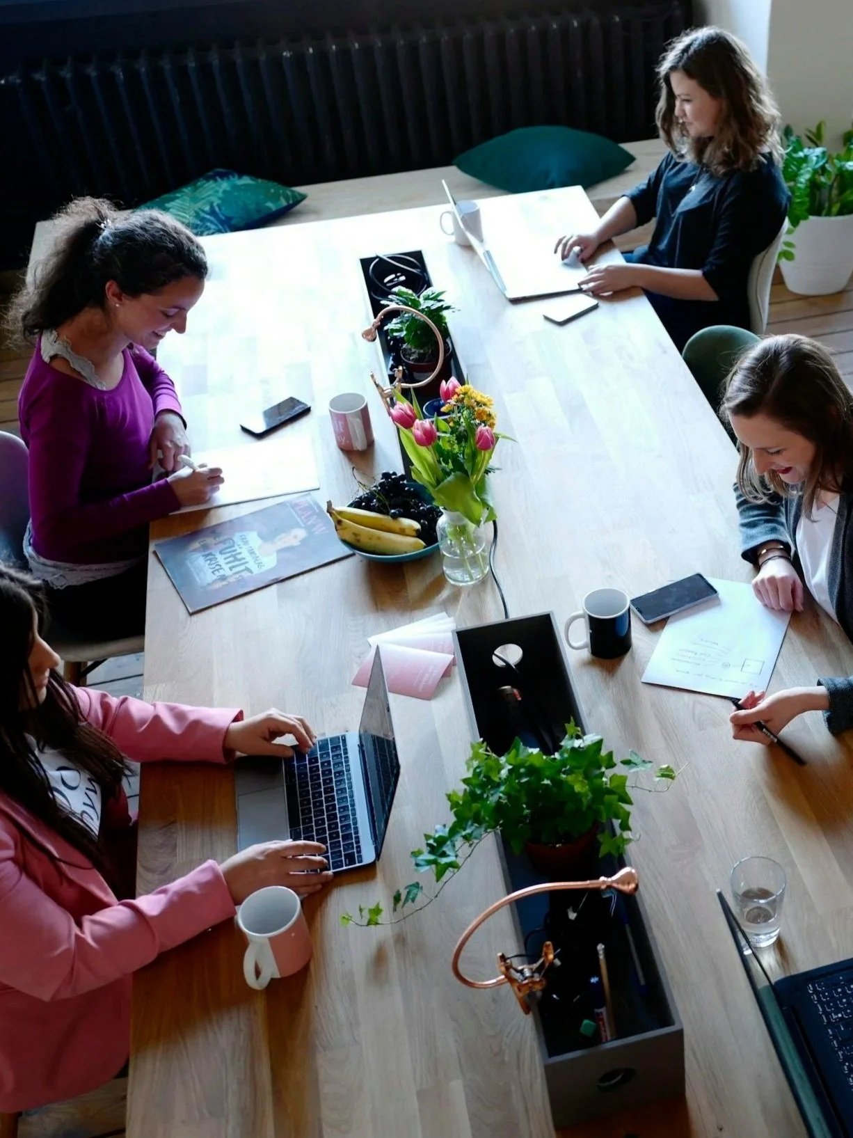 Several women working at a table simultaneously