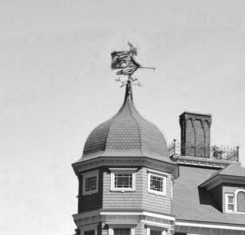 Rooftop of a Victorian-style Manoir Fitch Bay with a weather vane featuring a figure of a witch on a broomstick.