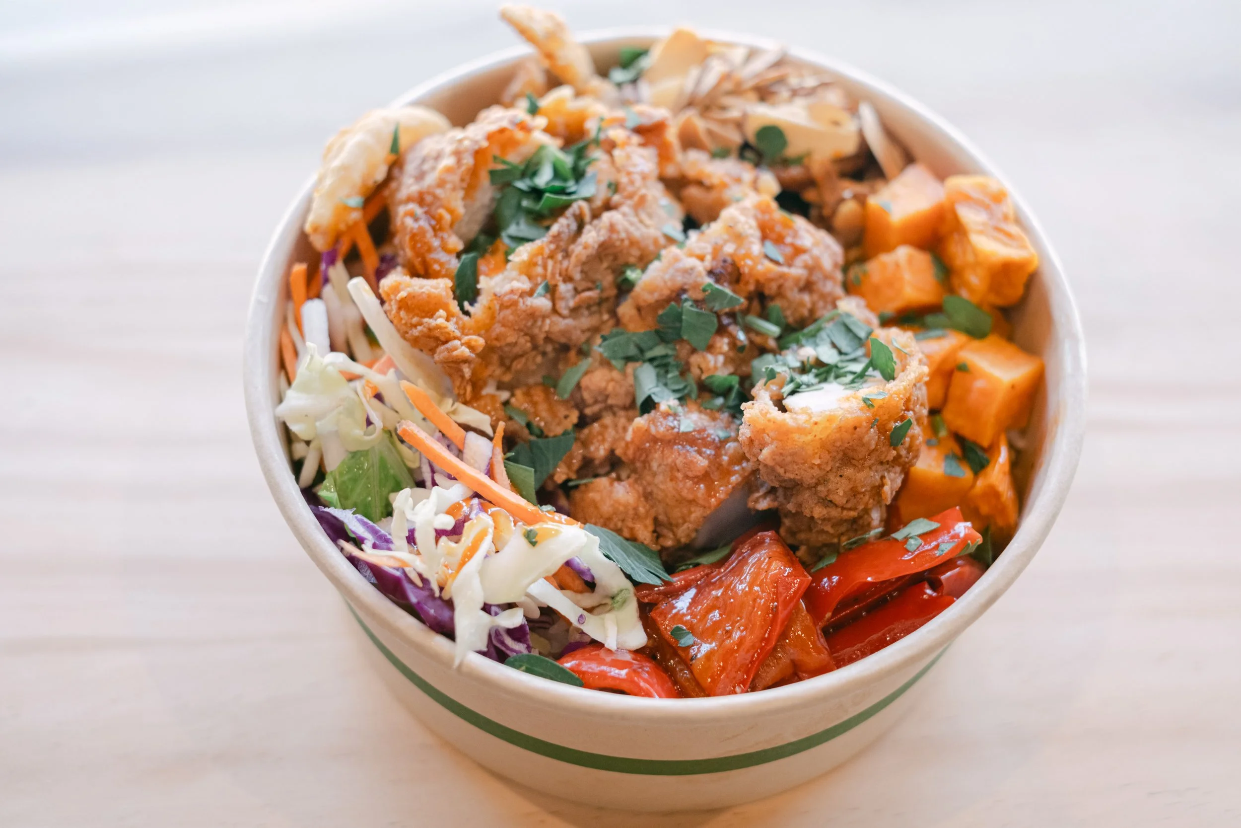 A bowl filled with various types of colorful Asian-style salads and toppings, including shredded vegetables, grilled meats, and herbs.