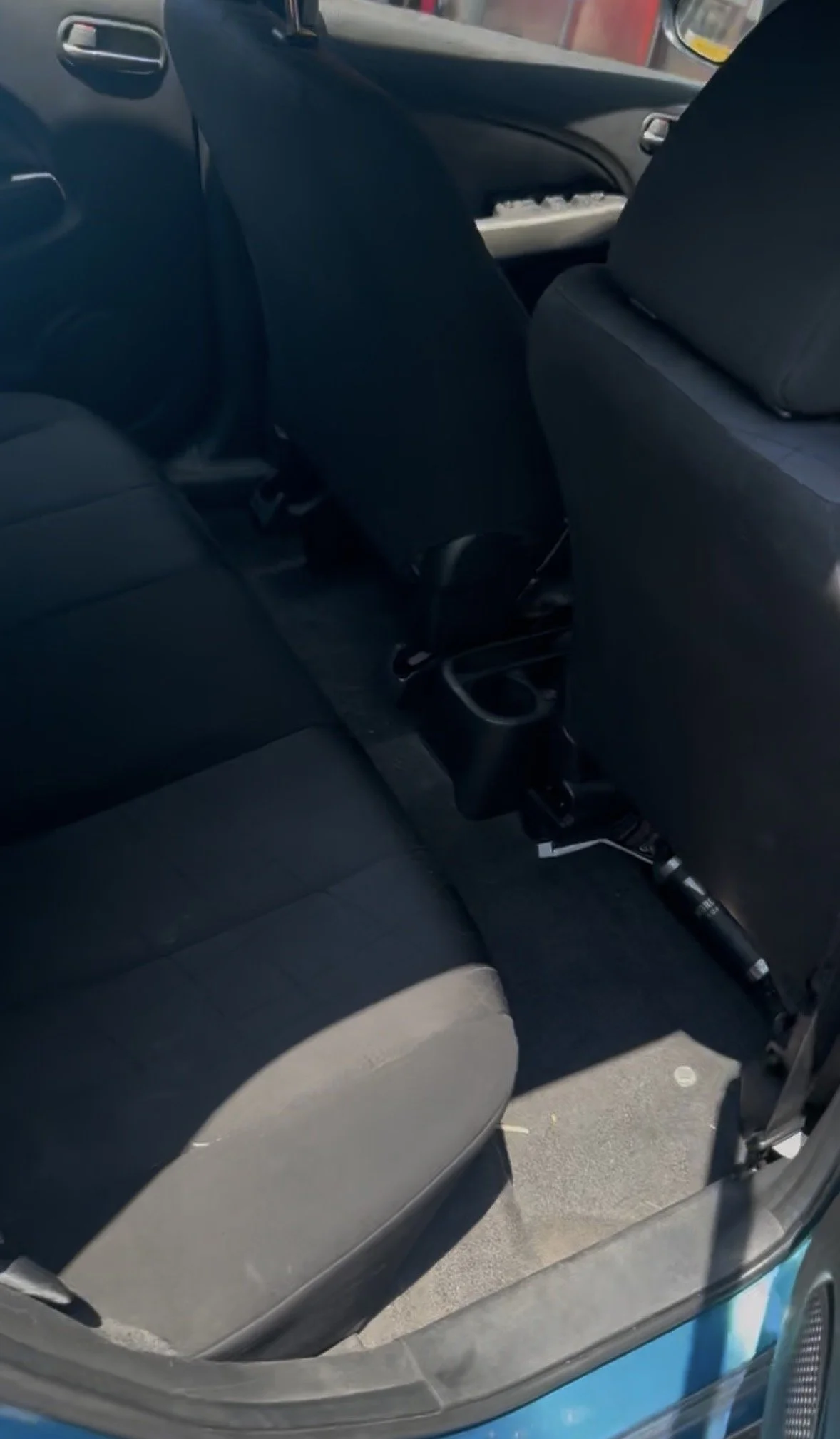 The interior of a car showing the back seat area and part of the front passenger seat, with a flashlight placed on the seat near the door.
