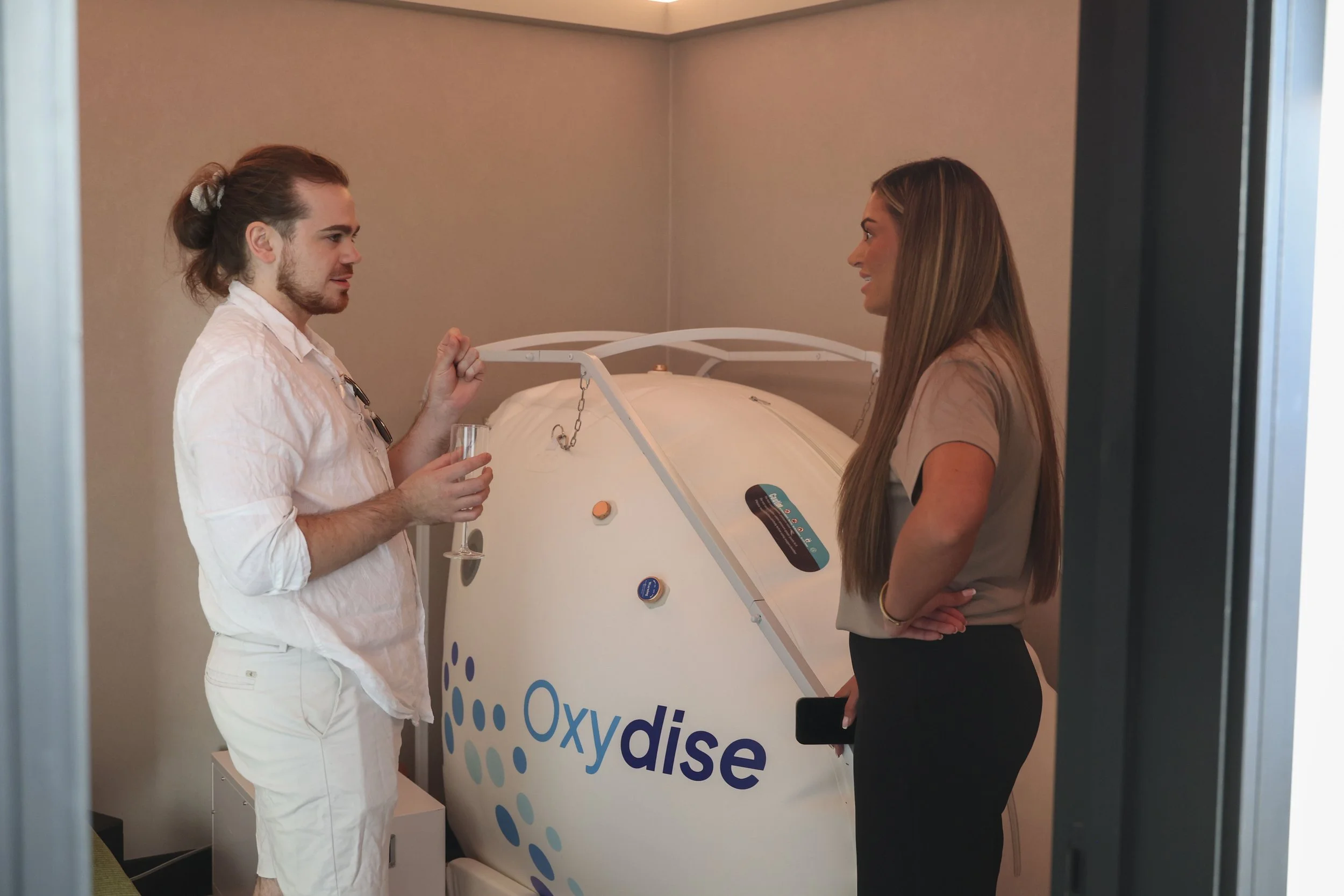 A Cold Room team member is explaining the benefits of Hyperbaric oxygen therapy (HBOT) to a visitor at The Cold Room's launch event in May.