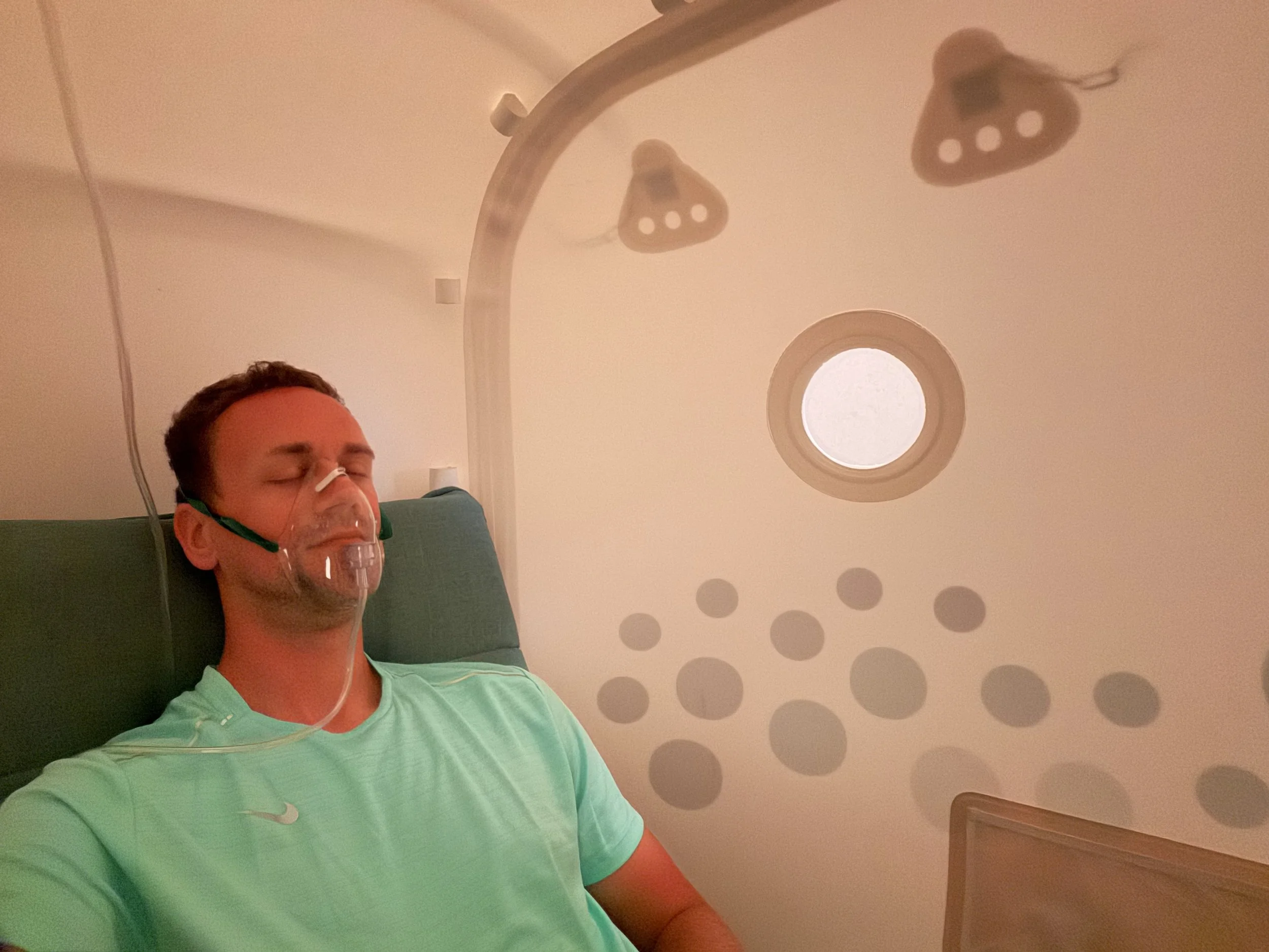 A client in The Cold Room's Hyperbaric oxygen therapy (HBOT) chamber wearing oxygen mask delivering 97% pure oxygen inside the pressurised chamber.