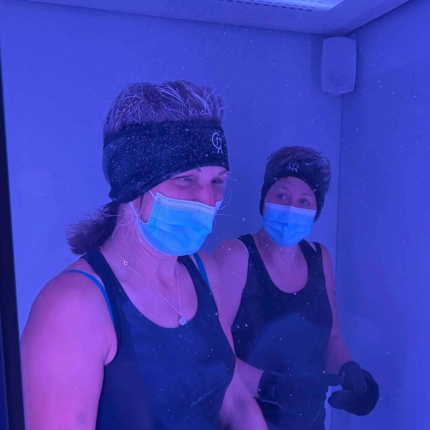 Two clients experiencing The Cold Room's Mecotec full-body cryotherapy chamber at -87°C. Frost is visible in their hair.