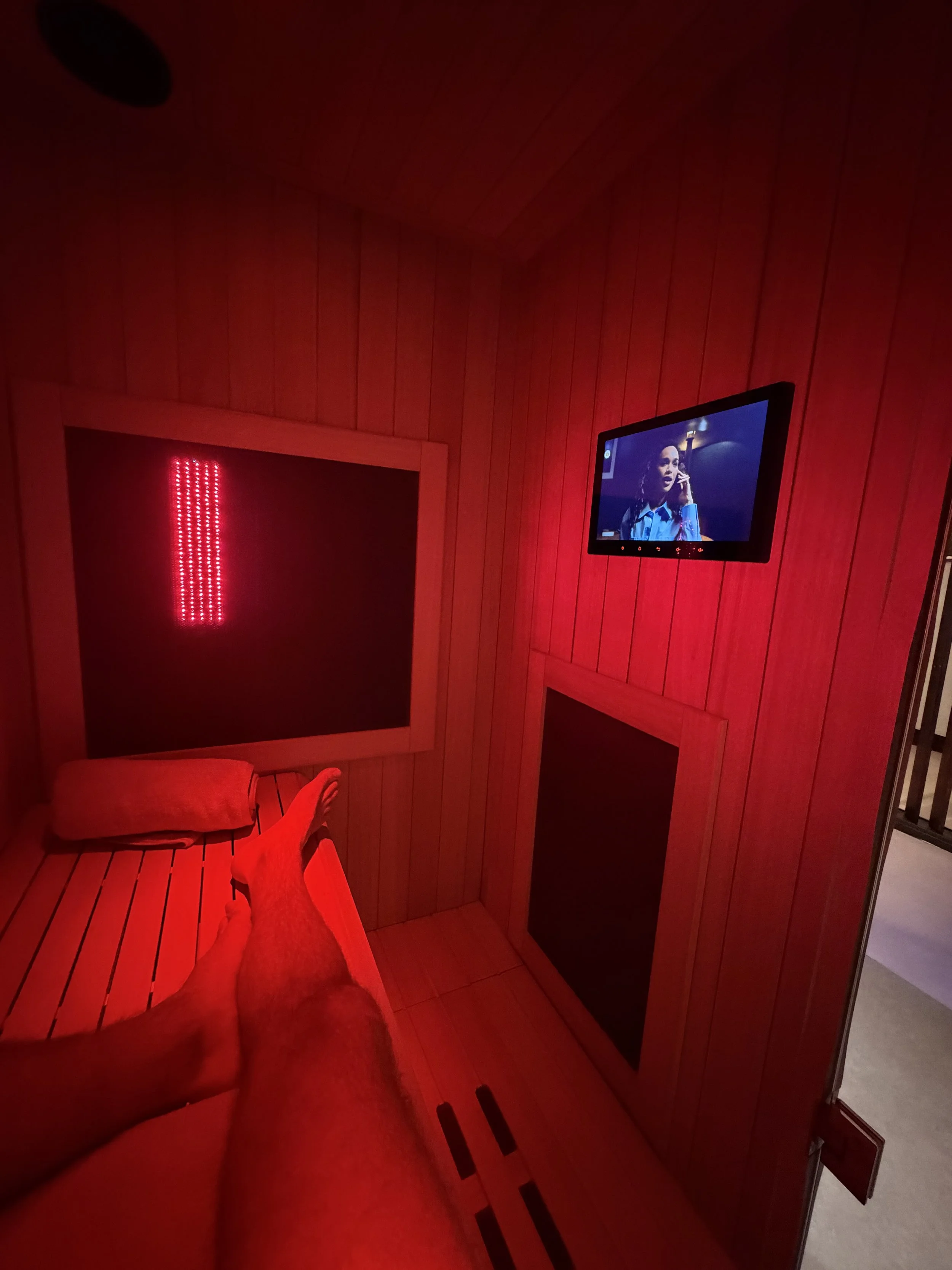 A client lays down in The Cold Room's Sunlighten infrared sauna whilst watching Netflix