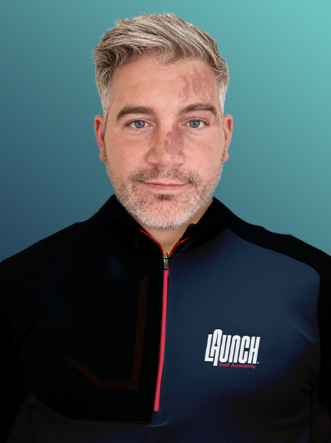 A middle-aged man with short gray hair and a beard, wearing a black and navy athletic jacket with the logo 'LAUNCH Golf Academy' on the chest, standing against a teal background.