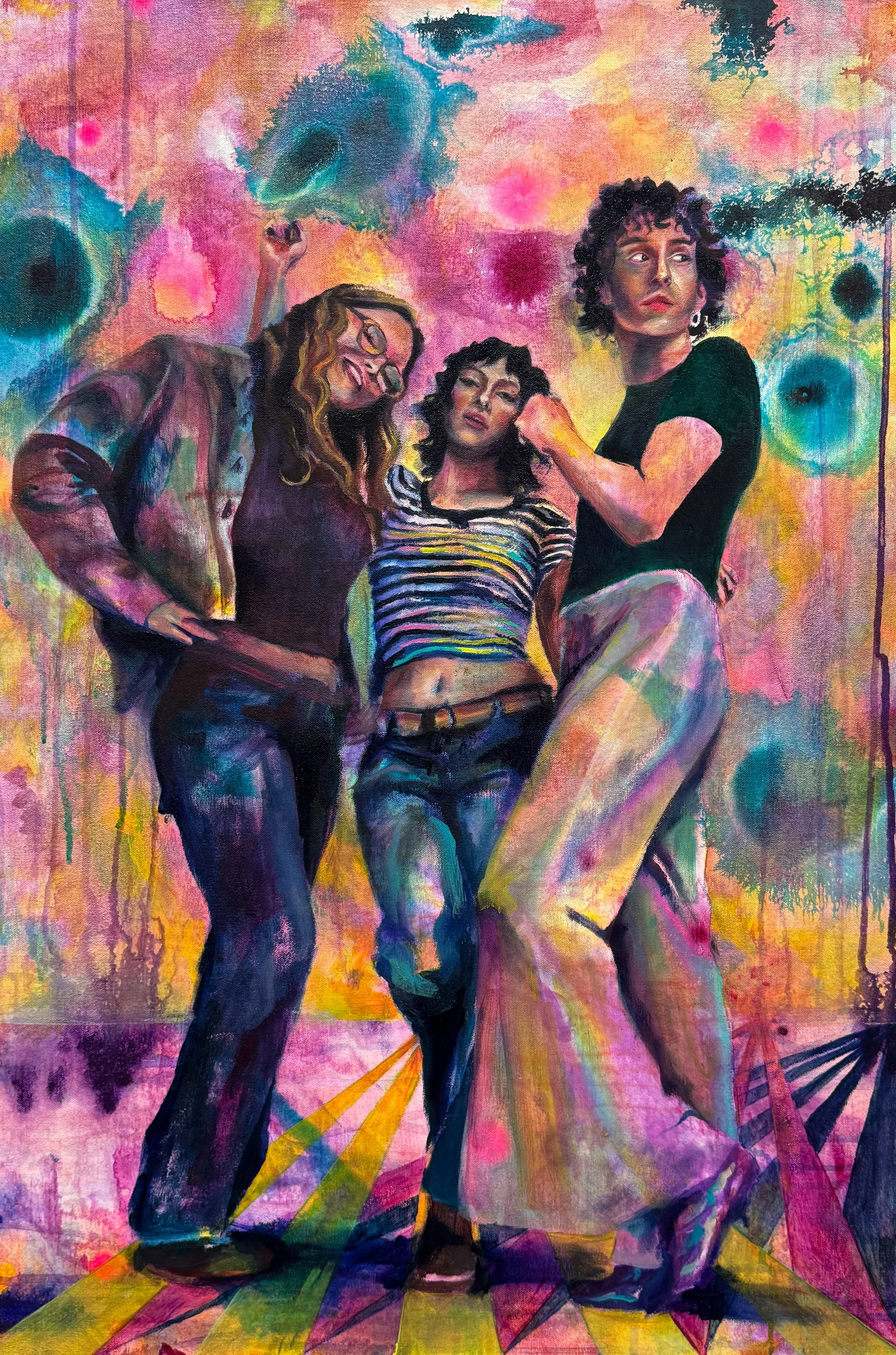 A colorful abstract painting of three women posing together, with a vibrant background of pink, orange, blue, and green hues, and diagonal yellow lines on the floor.
