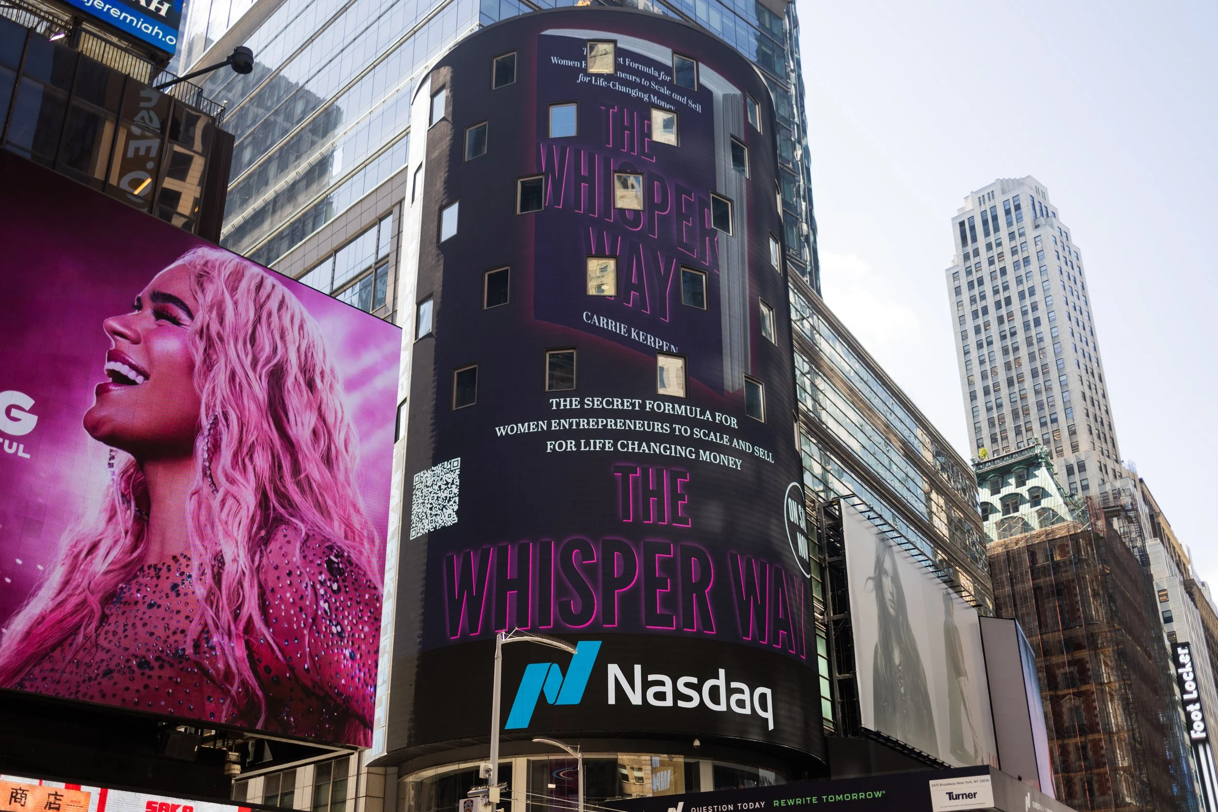 Cityscape featuring tall buildings with electronic billboards, including a large pink billboard of a laughing woman and a digital display promoting Carrie Kerpen's book, 'The Whisper War', on Nasdaq.
