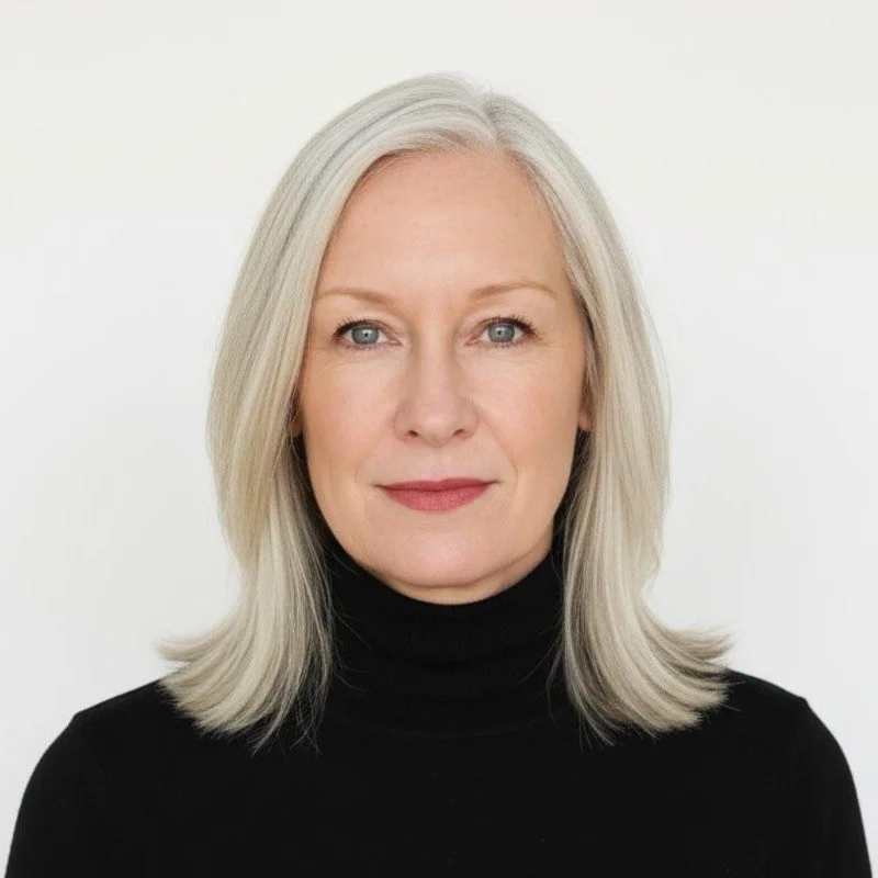 Portrait of a middle-aged woman with long gray hair, blue eyes, and wearing a black turtleneck against a plain white background.
