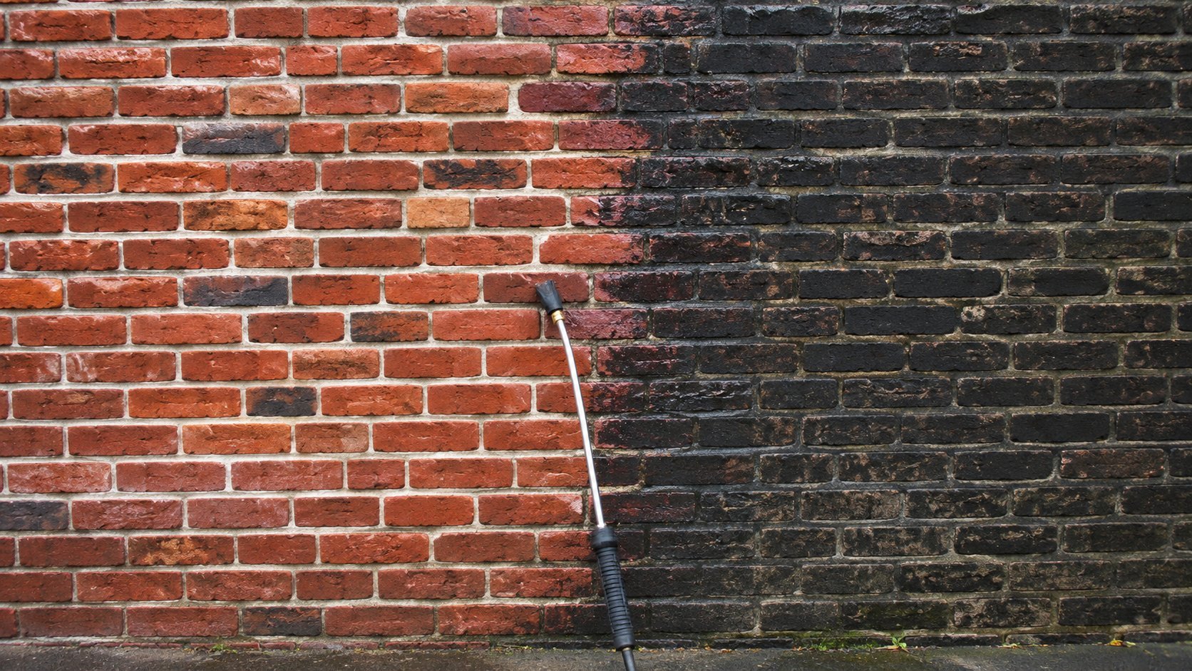 Heritage brick wall half cleaned showing bright restored brick beside dark grime