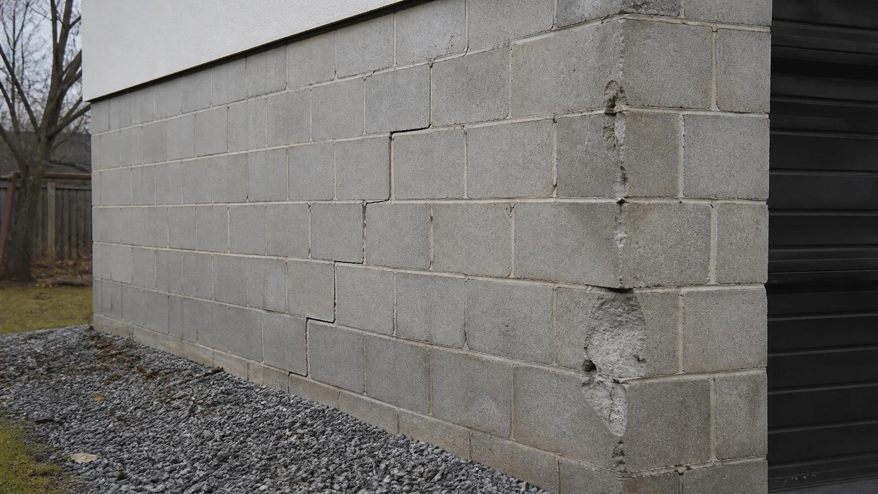 Concrete block foundation wall with a stair-step crack and a crumbling corner