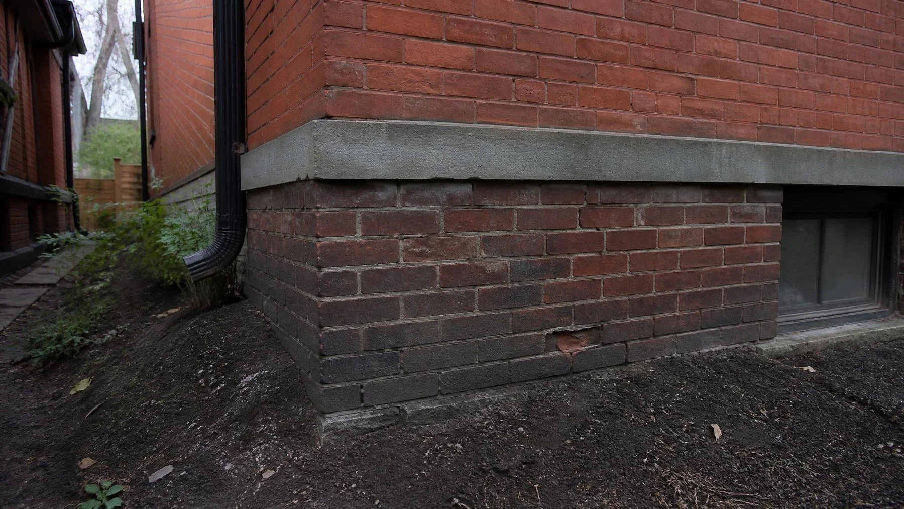 Exposed brick foundation wall showing mortar deterioration below the exterior brickwork