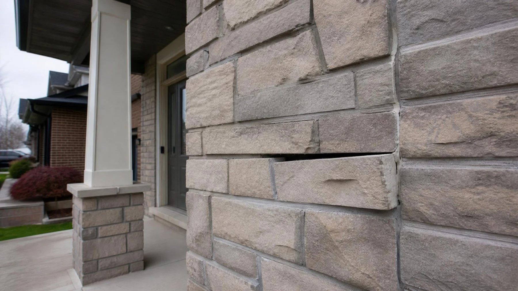 Stone veneer wall at a home entrance with one piece slightly separated