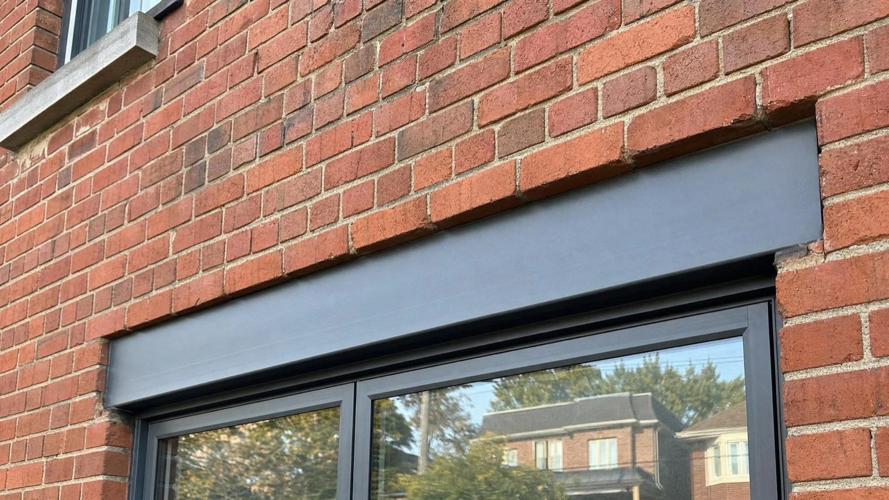 Steel lintel supporting a red brick wall above a residential window