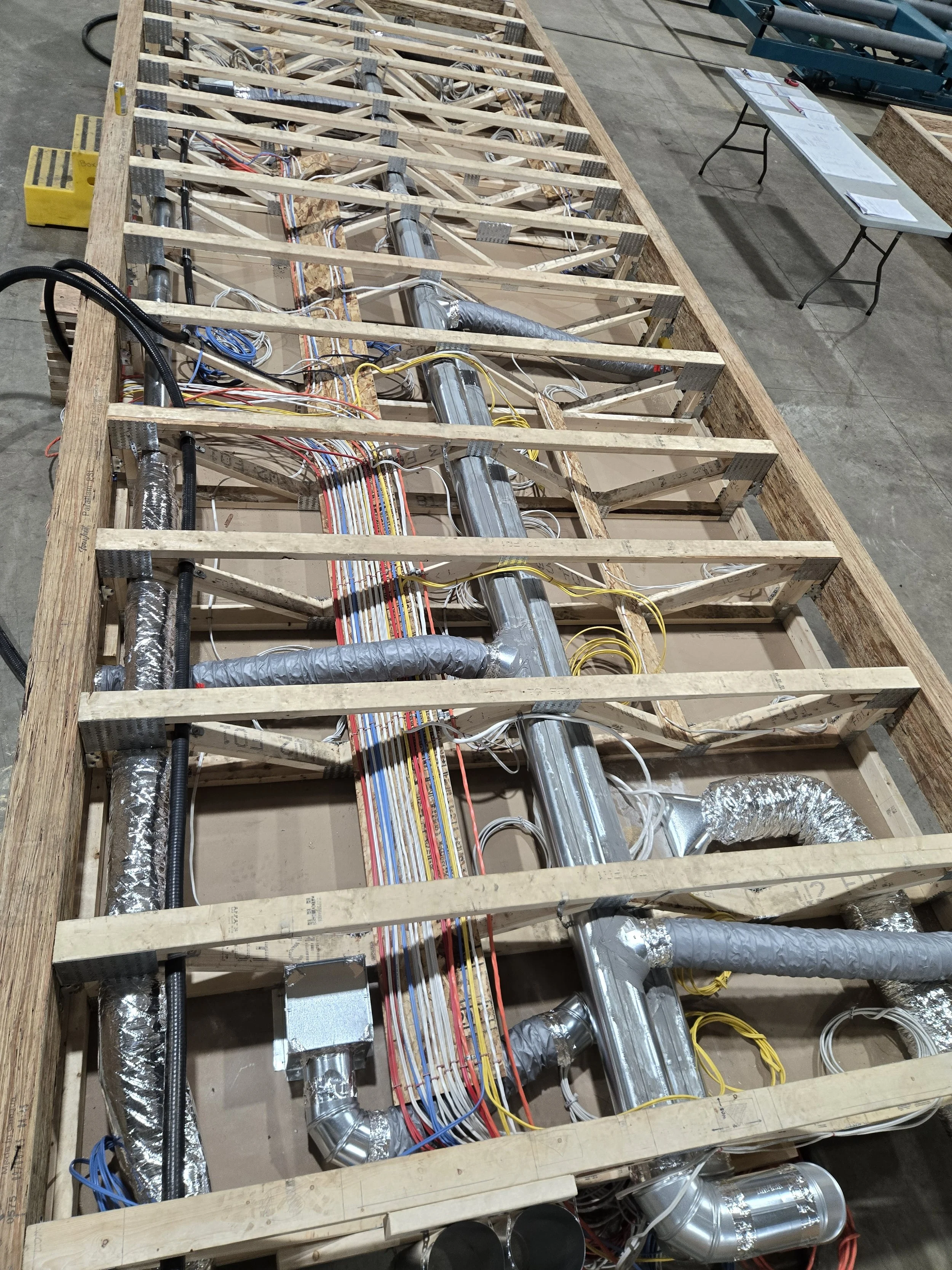 View of an unfinished building frame with exposed framing, wiring, and ductwork in a construction site.