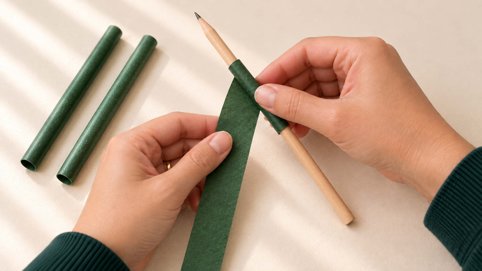 Vida’s hands shaping dark-green paper leaves around green paper stems for the three-dimensional tulip garden.