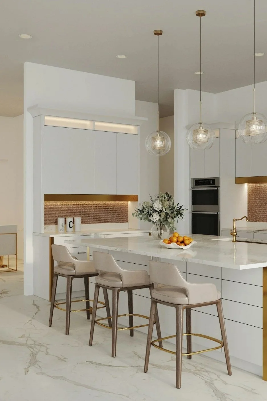 Modern kitchen with white cabinetry, marble island, three beige chairs, gold accents, floral centerpiece, and hanging pendant lights.