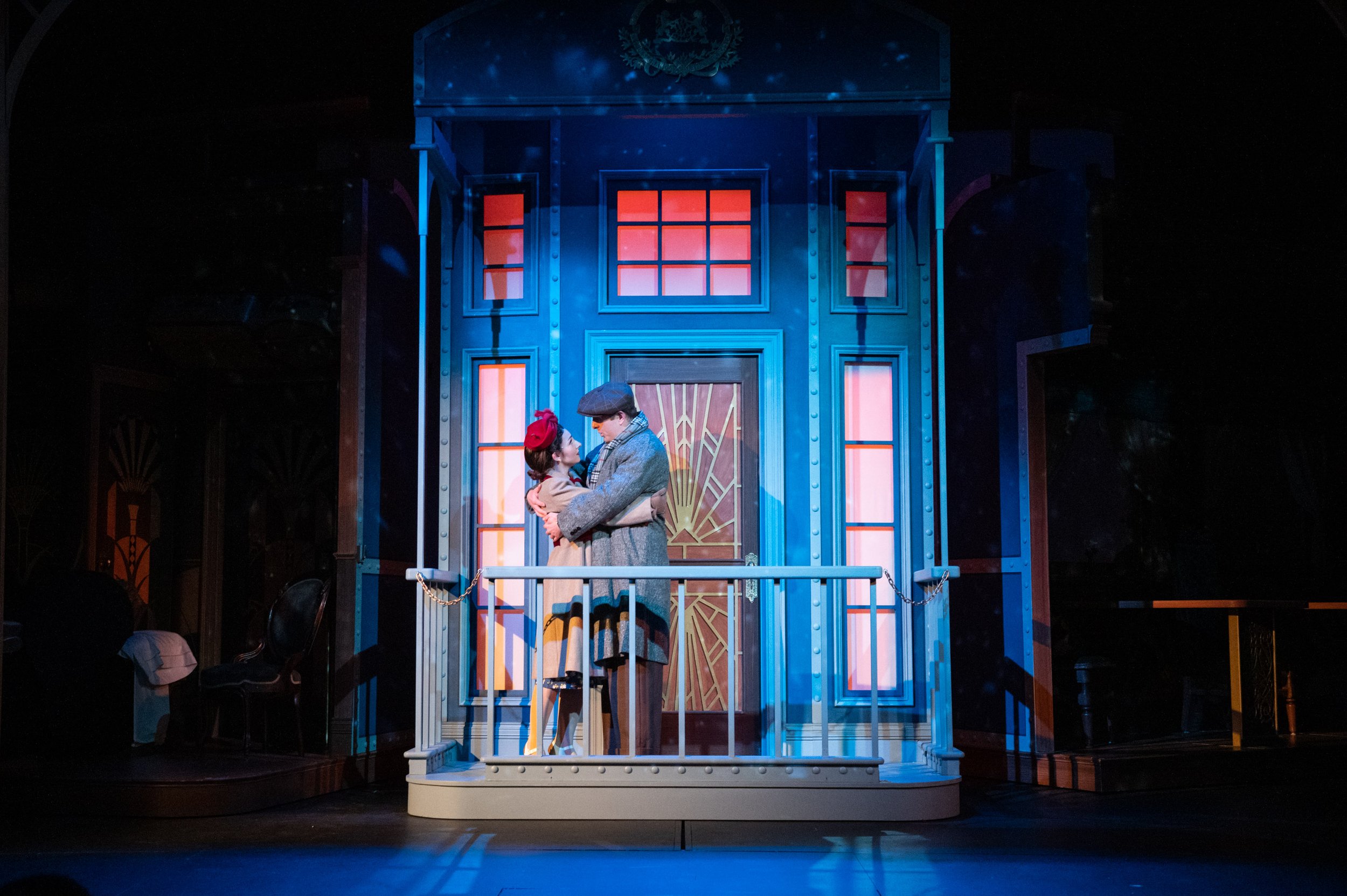 Murder on the Orient Express at the Barter Theatre of Abingdon, VA.  Scenic design by Derek Smith.  Two actors on a theater stage, standing on a train caboose with a door and windows behind them, engaging in a romantic scene.