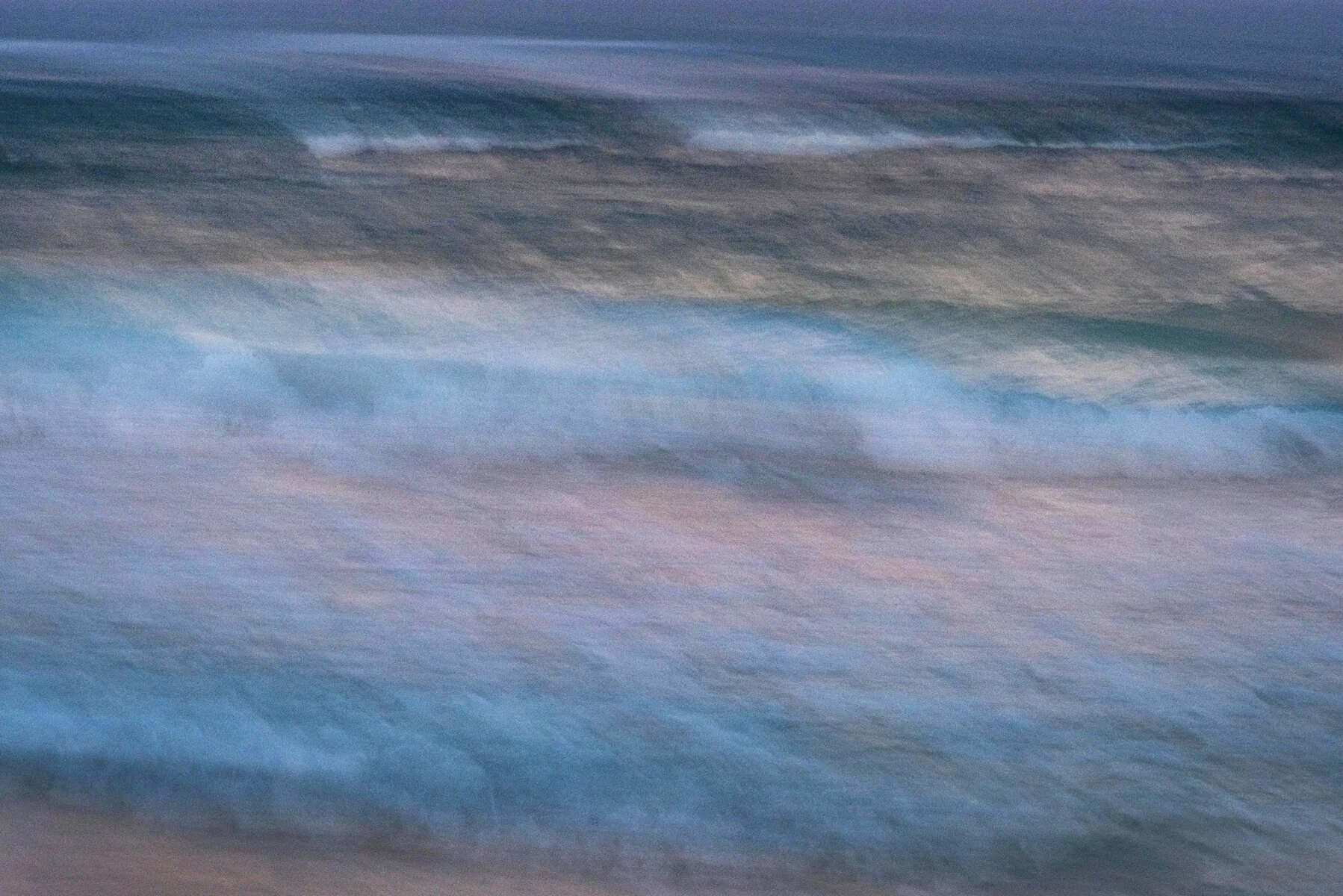 Blurred image of ocean waves with blue and gray tones.