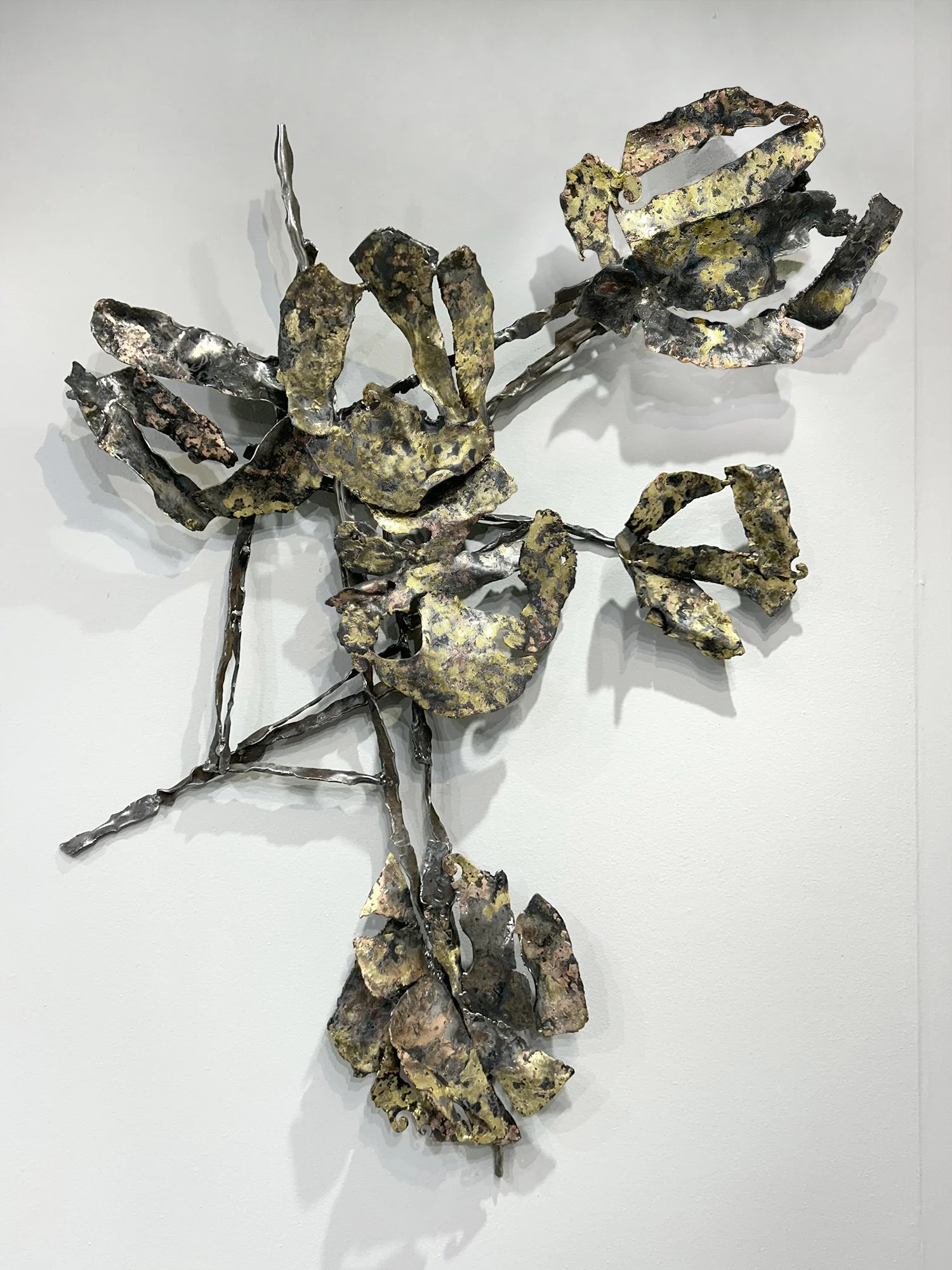 Metal sculpture of a dragonfly with detailed wings and body, mounted on a wall.