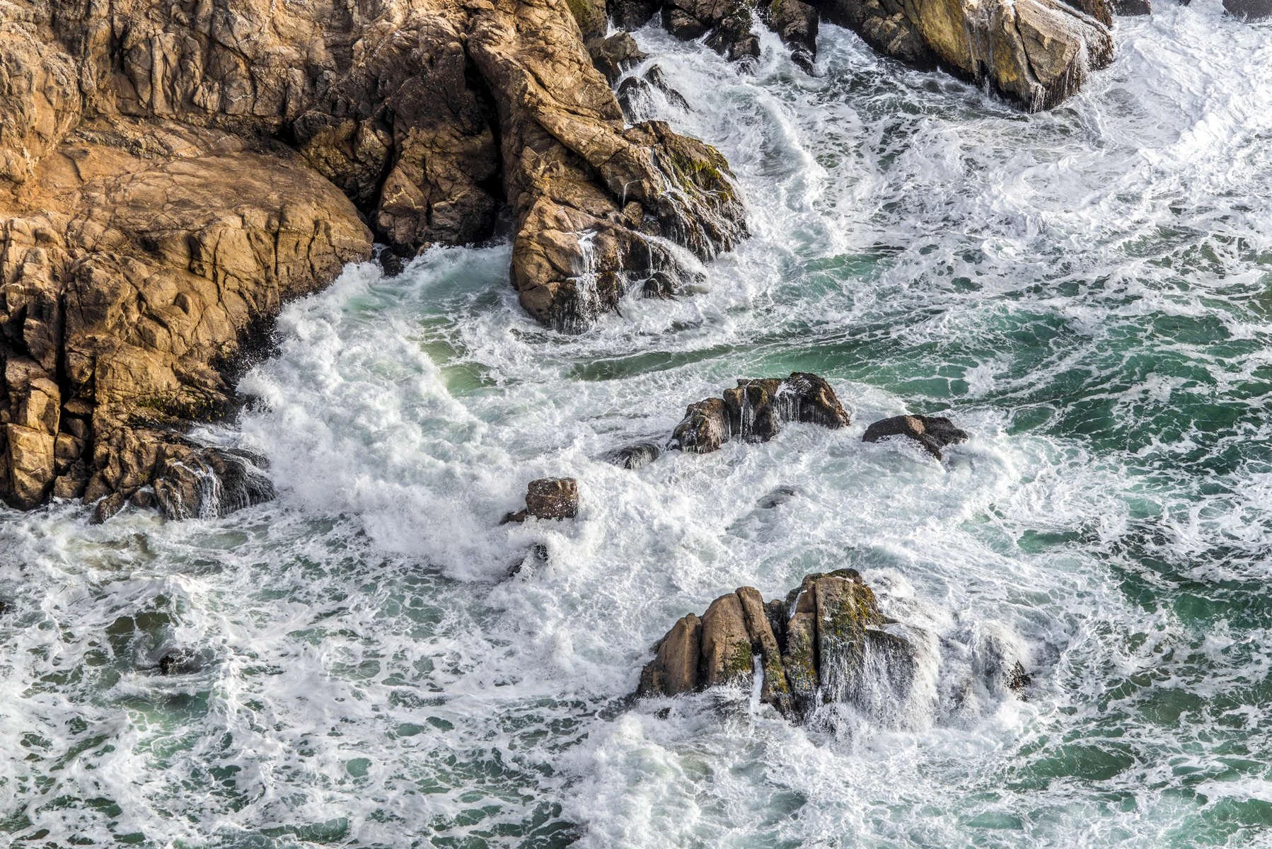 Waves crashing against rocks along a rocky coastline.