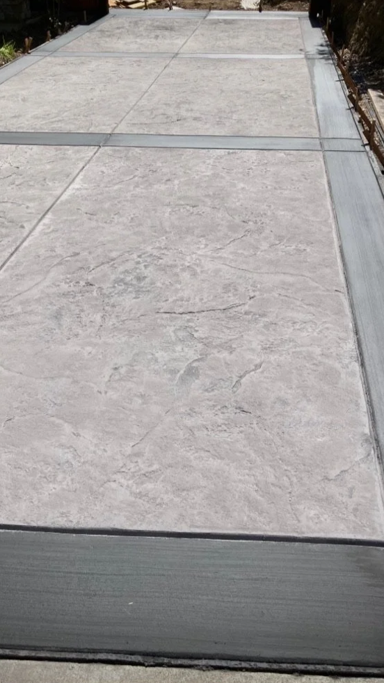 Close-up of a section of a concrete or stone paved surface with metal or aluminum edging on the sides.
