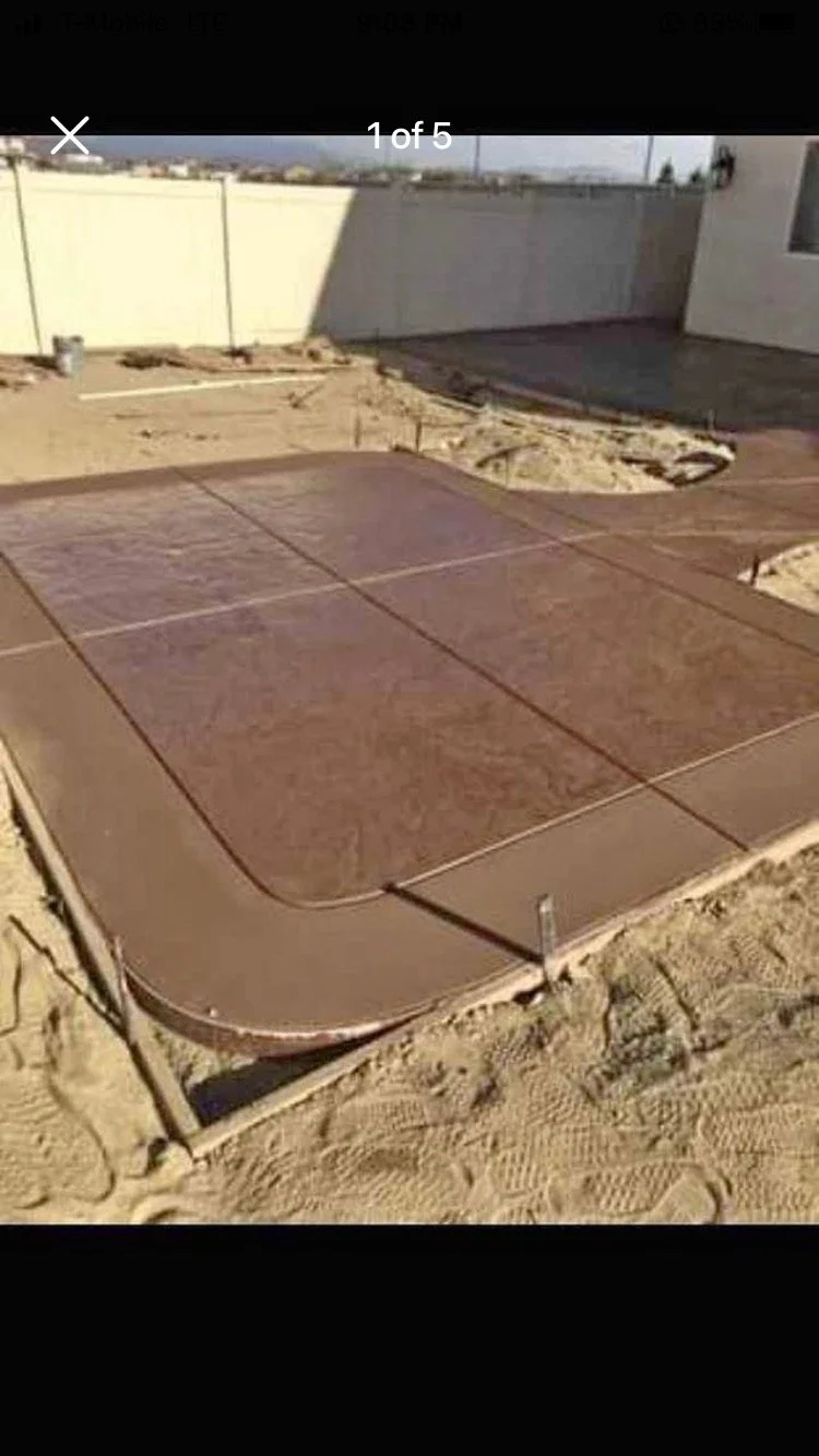 Closed wooden patio table on a concrete patio in a backyard under construction.