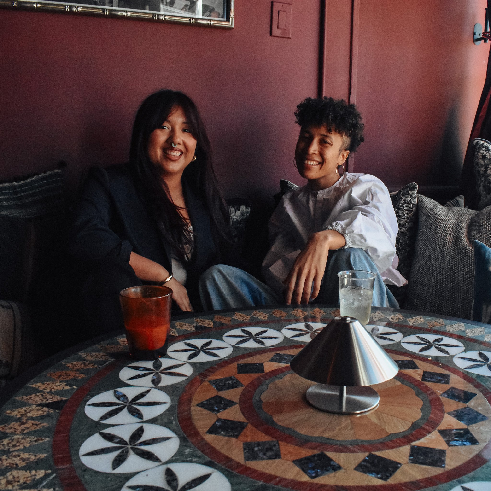 Two women sitting together at a table in a restaurant, smiling and enjoying their time.