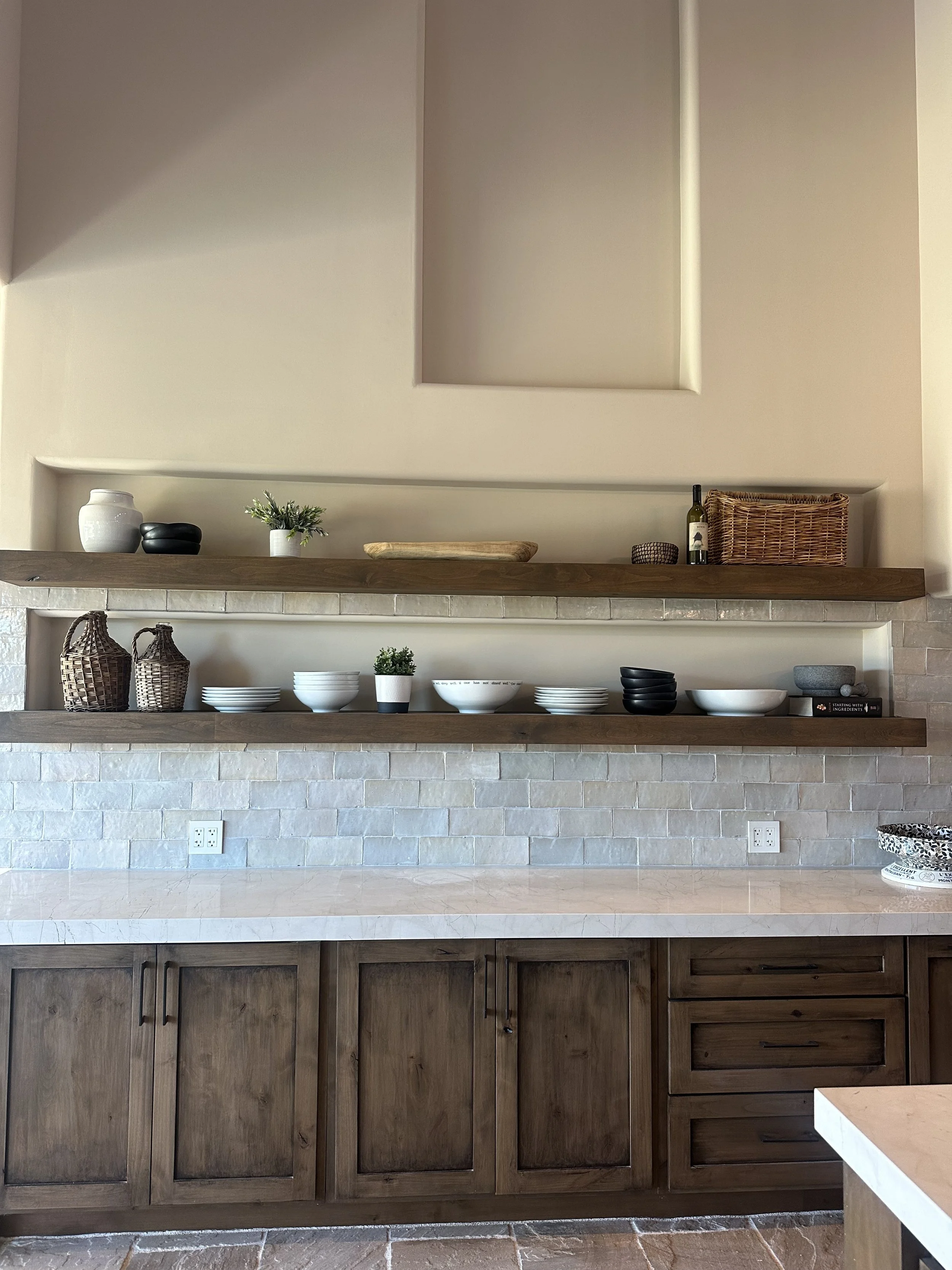 Kitchen with wooden cabinets, open shelves, and a collection of bowls, plates, and decorative items on the shelves.