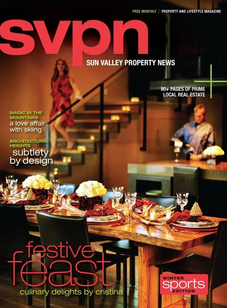 The cover of a magazine titled 'SVPN Sun Valley Property News' featuring a holiday dinner table set with plates, glasses, and floral centerpieces, a staircase with a woman descending, and a woman standing at a bar in the background, with headlines ab