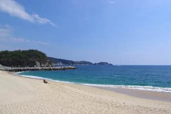 Empty sandy beach with ocean waves and a clear sky