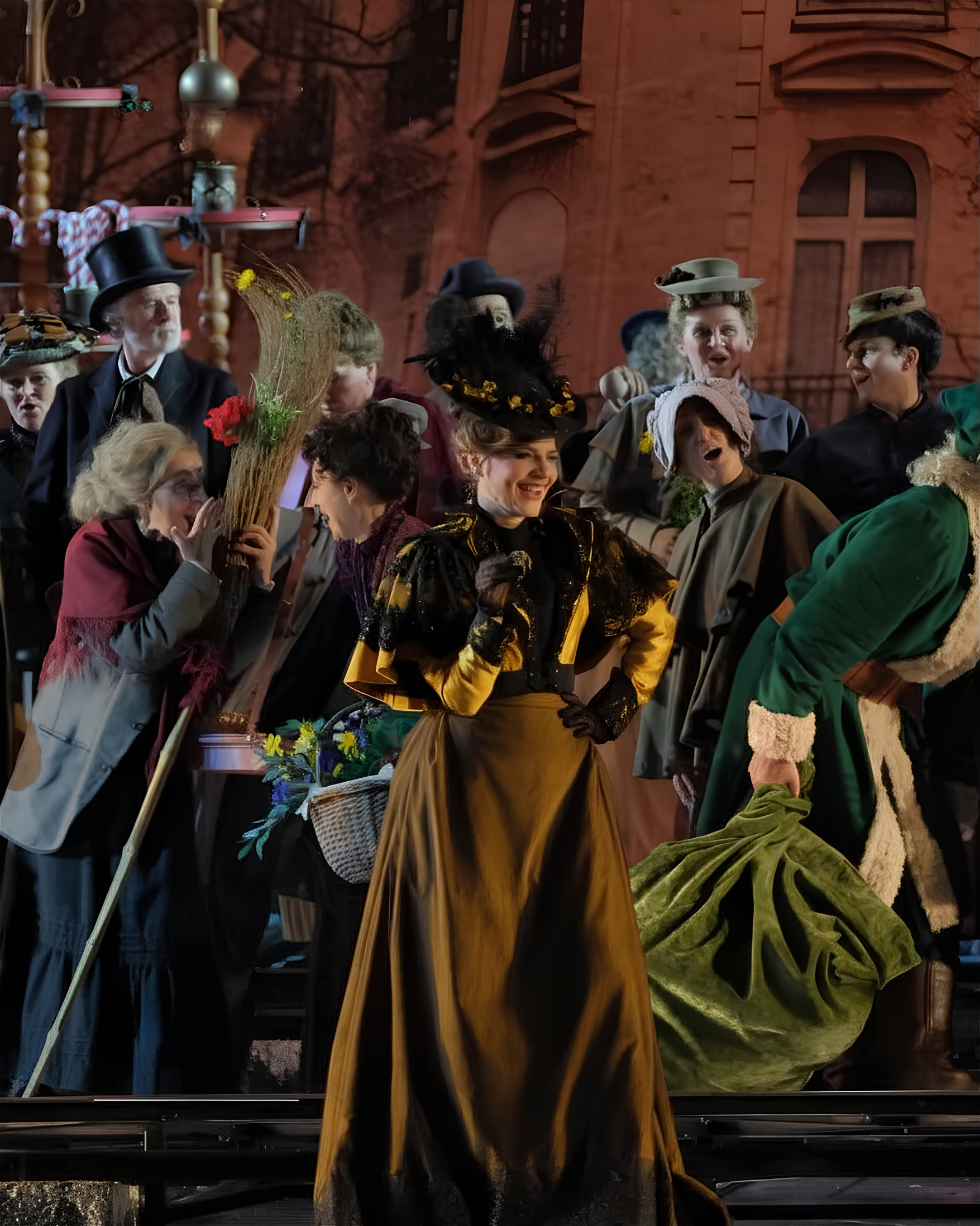 Francesca Pia Vitale soprano, interpreta Musetta, e gruppo di persone in costume d'epoca, alcune indossano cappelli decorati, in un ambiente con sfondo di edifici storici di mattoni.