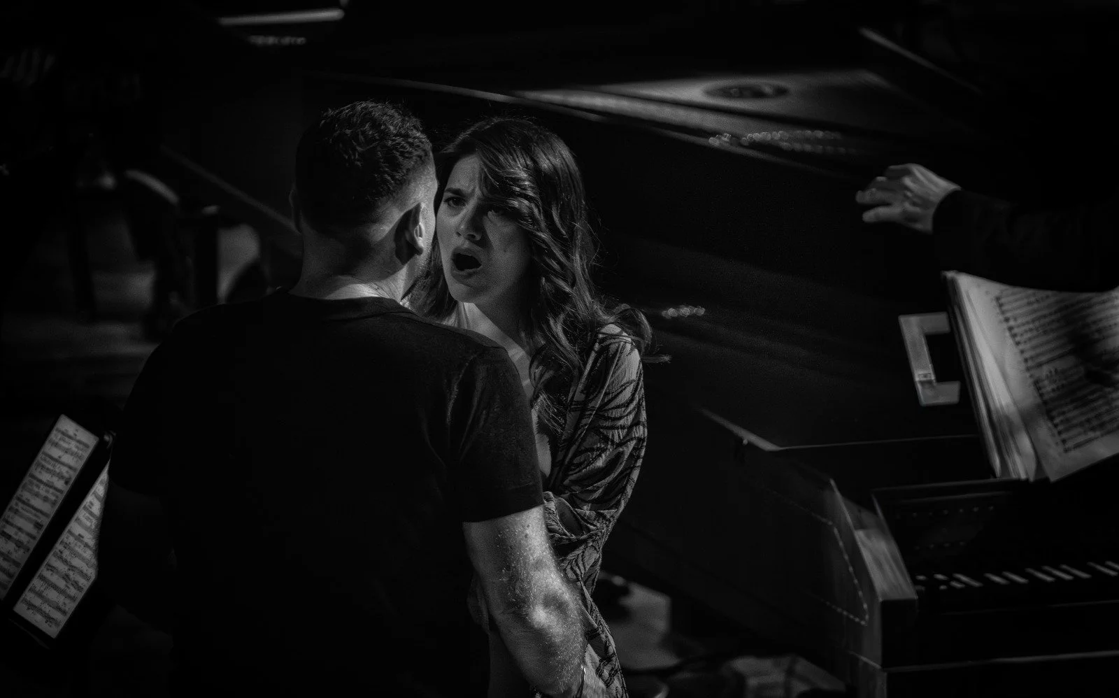 Due persone, un uomo e una donna, in un momento intenso di dialogo, vicino a un pianoforte, in un ambiente probabilmente di studio musicale. La scena è in bianco e nero.