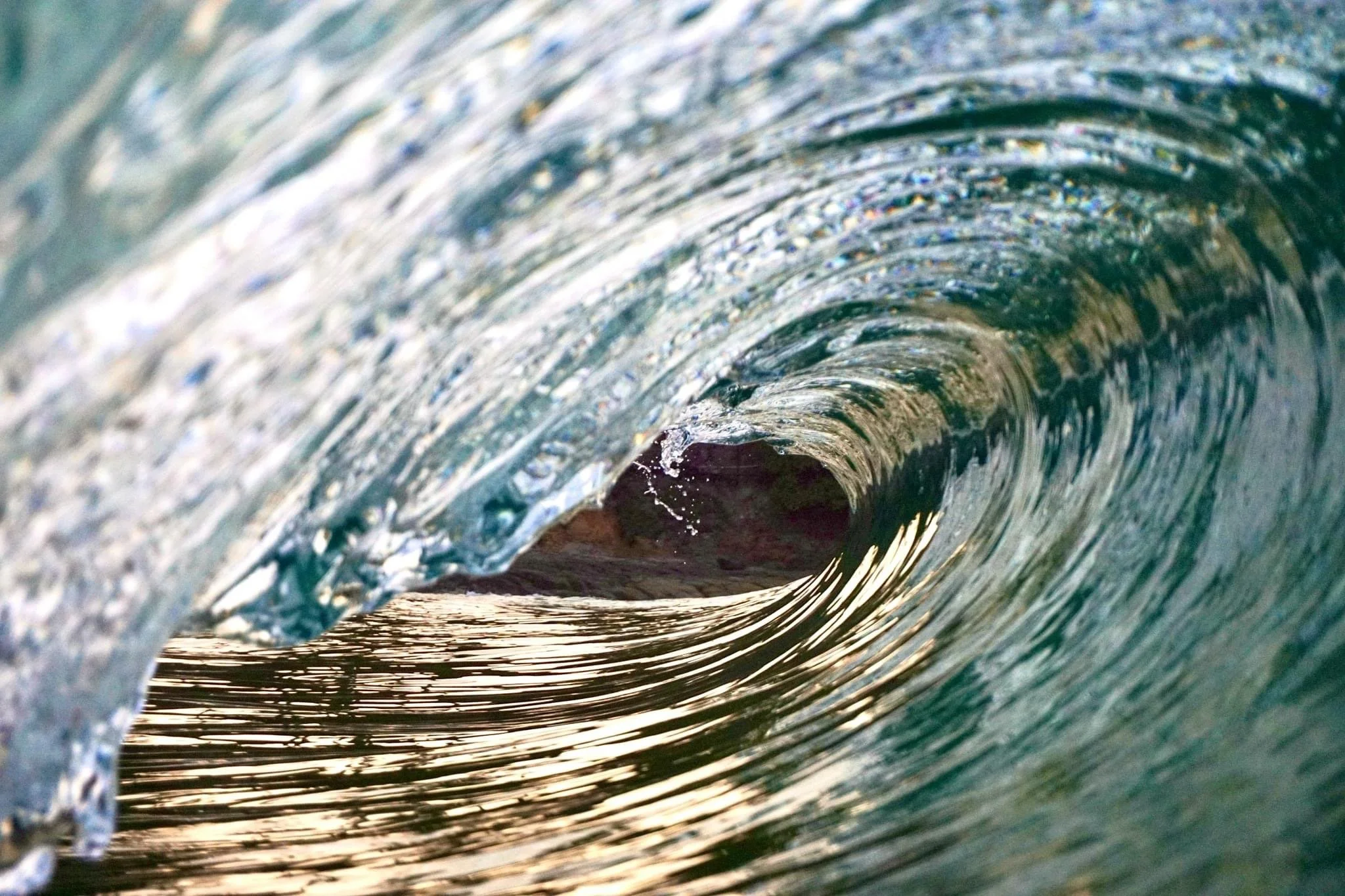 Inside a ocean wave tunnel, showing the wave's curling shape and surface water reflections.