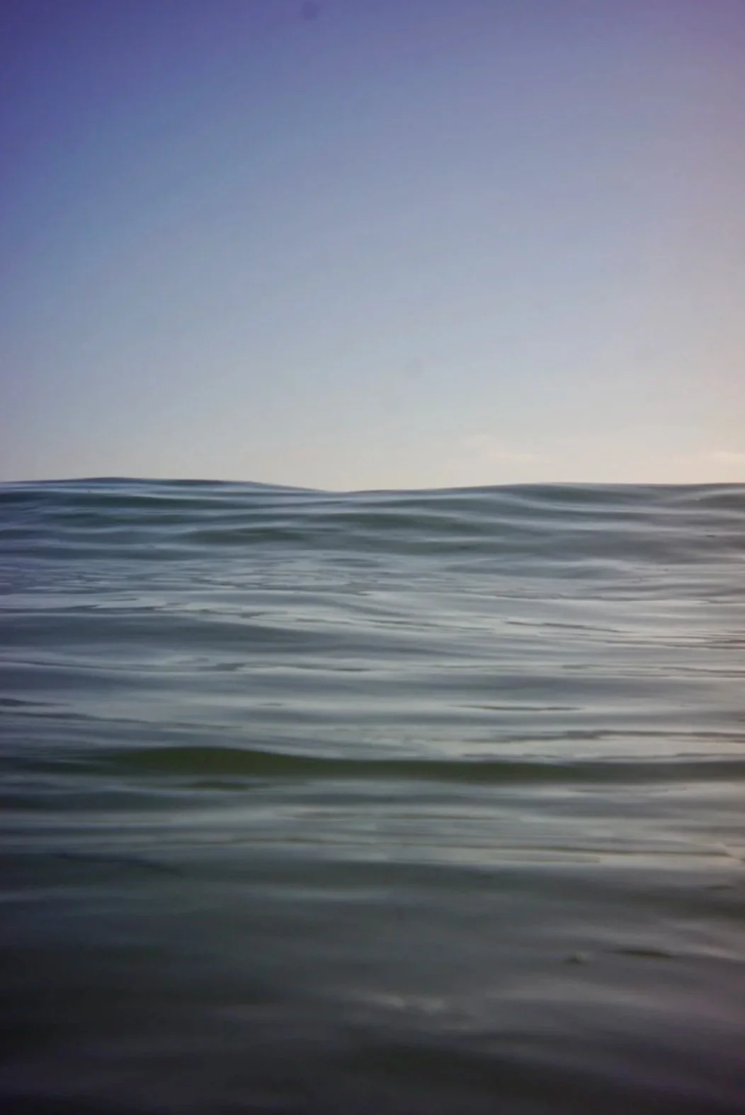 An ocean scene with gentle waves and a clear sky at sunrise or sunset.