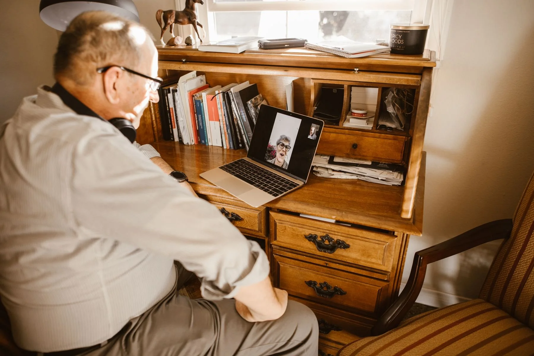 Man speaking with another person on a laptop video call at home.