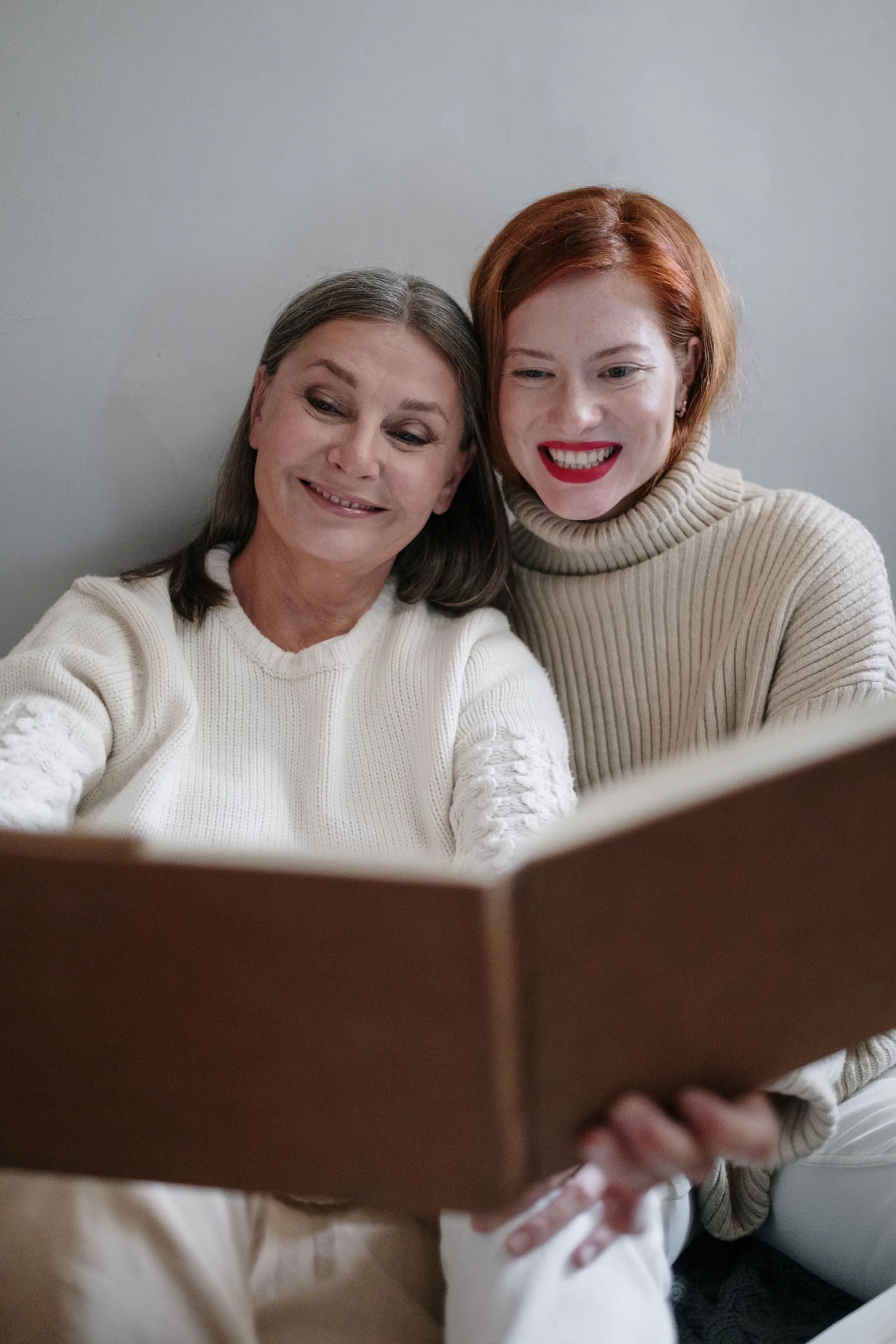 Two women sharing a book at home.