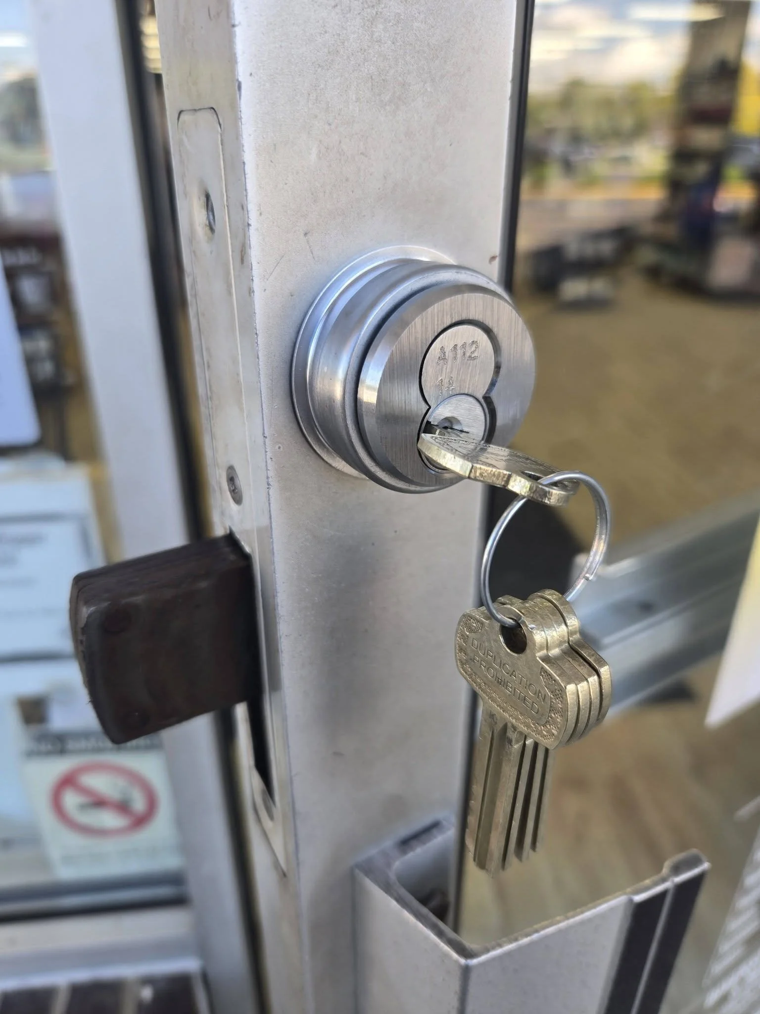 Close-up of a metal key inserted into a keypad lock with a keyring attached, on a metal door.