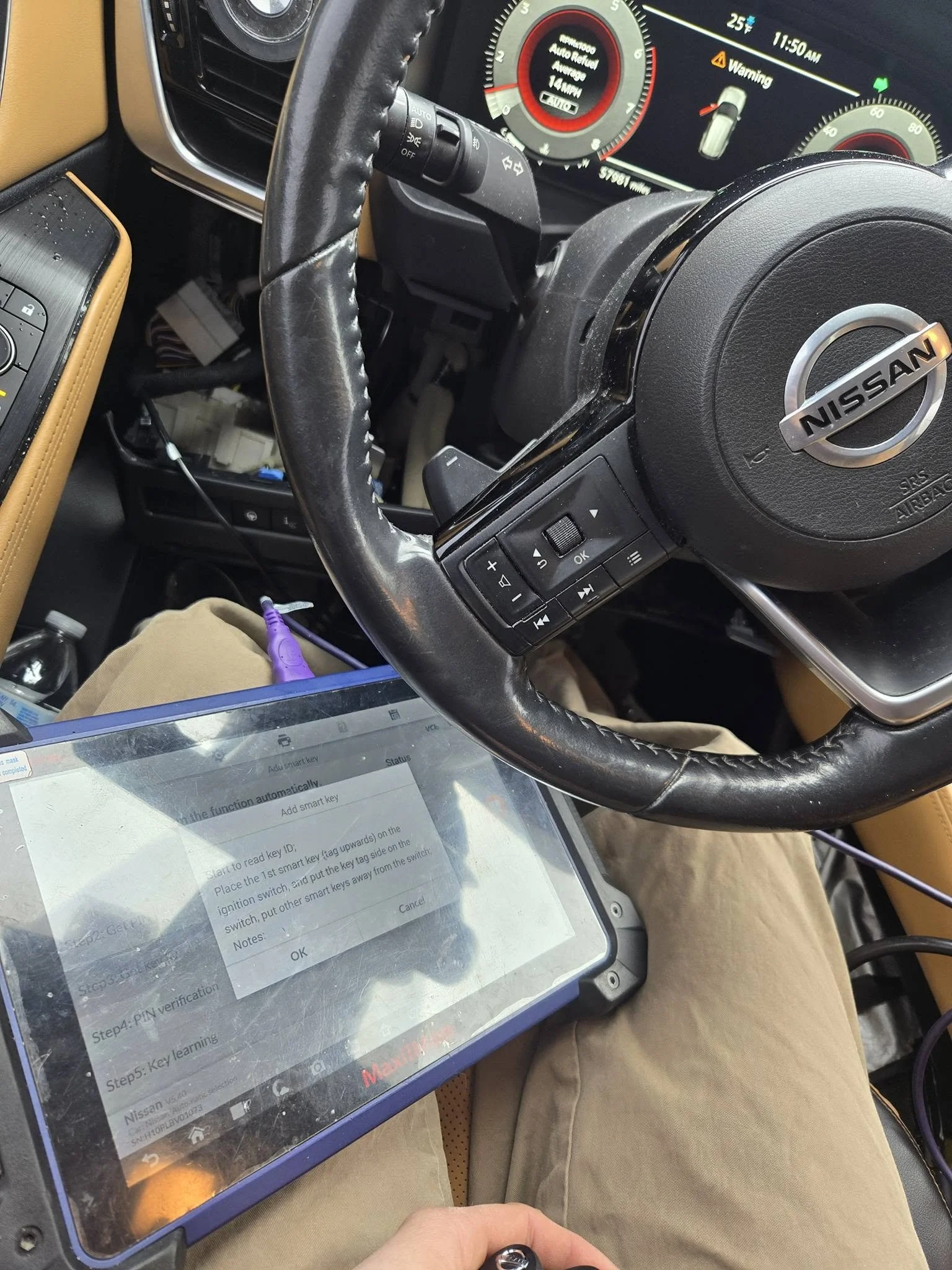 A Nissan vehicle dashboard showing the steering wheel with mounted controls, a speedometer. Locksmith Programming Nissan Car Key. Proximity key programming.