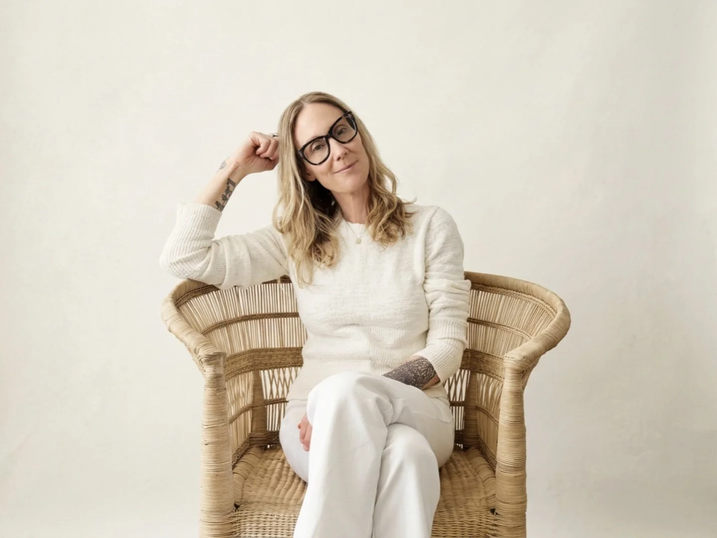 Kelly Chapman, LCSW, seated in a rattan chair, resting one hand near her head.
